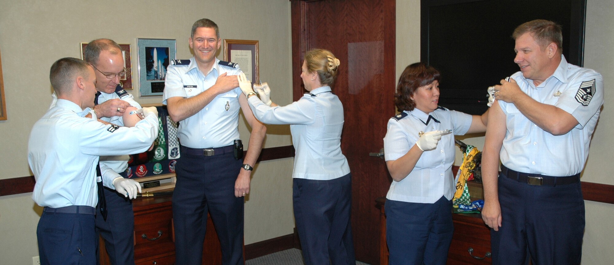Airman 1st Class Cody Bohlke, 341st Medical Operations Squadron, Lt. Col. Martha Johnston, 341st MDOS,  and Lt. Col. Lourie Moore, 341st Medical Group, administer flu shots to Col. Michael Fortney, 341st Missile Wing commander, Col. Paul Gydeson, 341st MW vice commander and Chief Master Sgt. Steve Sargent, 341st MW command chief Oct. 20 in Colonel Fortney's office. The top three leadership members are always the first to be immunized. (U.S. Air Force photo/ Airman 1st Class Dillon White)  