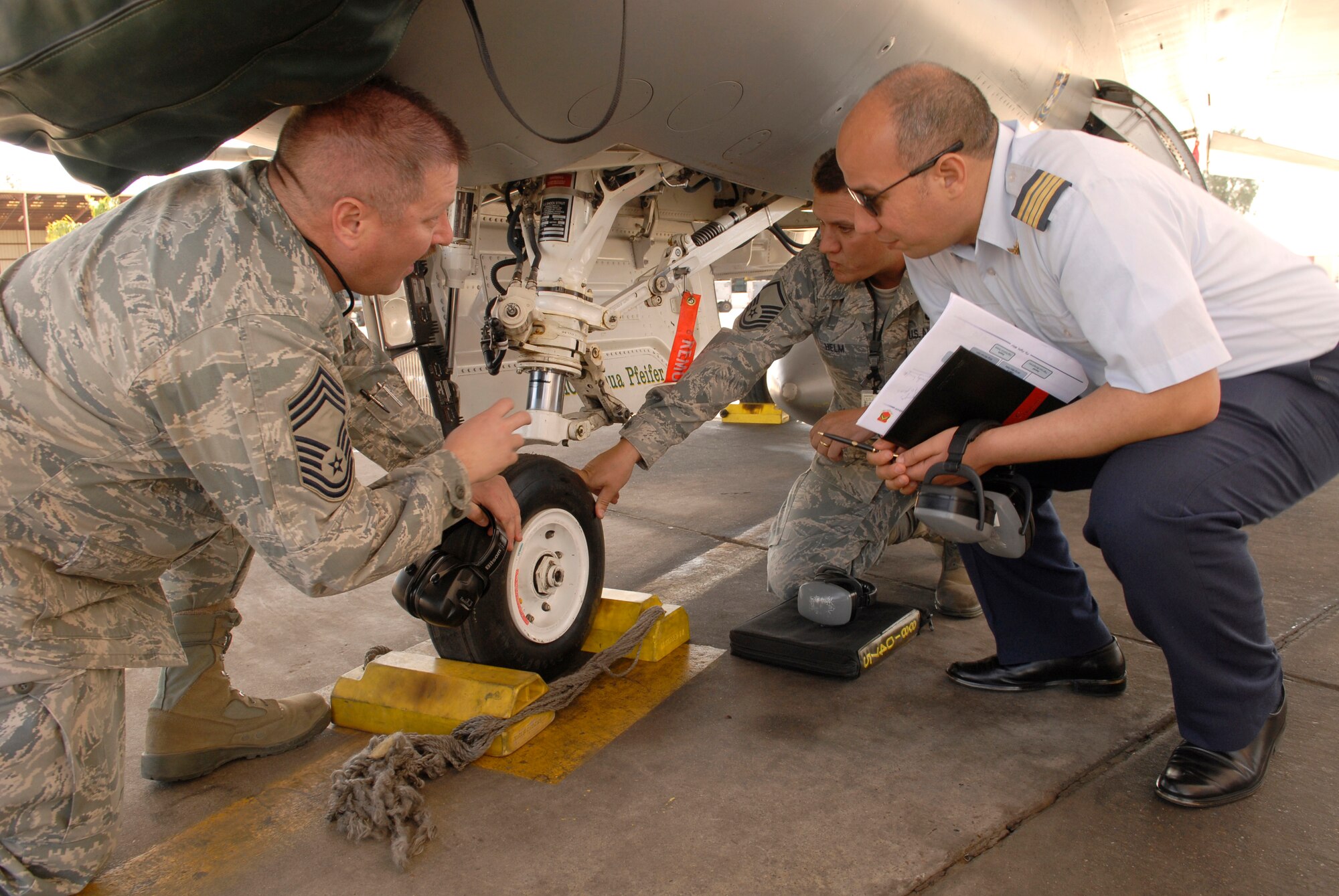 Chief Master Sgt. Robert Britton and Master Sgt. Michael Helm, 310th Aircraft Maintenance Unit, discusses features of the F-16 nose landing gear to a member of the Royal Moroccan air force on March 12. Members of the RMAF visited Luke Air Force Base, Ariz., to learn about Air Force maintenance procedures. (U.S. Air Force photo/ Staff Sgt. Ian Dean)