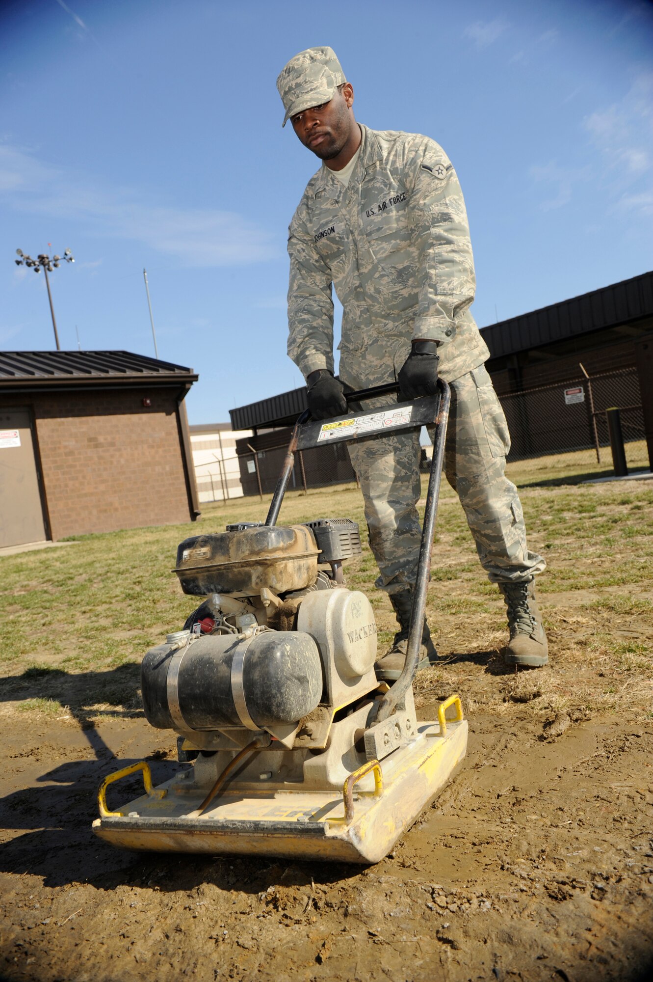 Airman Cory Johnson, 87th Civil Engineer Squadron Heavy Equipment Shop operator, uses a hand tamper to compact the soil after a utility dig March 12. The hand tamper is also used to prepare surfaces before laying down asphalt, concrete, or sod and helps speed up the settling process. (U.S. Air Force photo/Carlos Cintron)