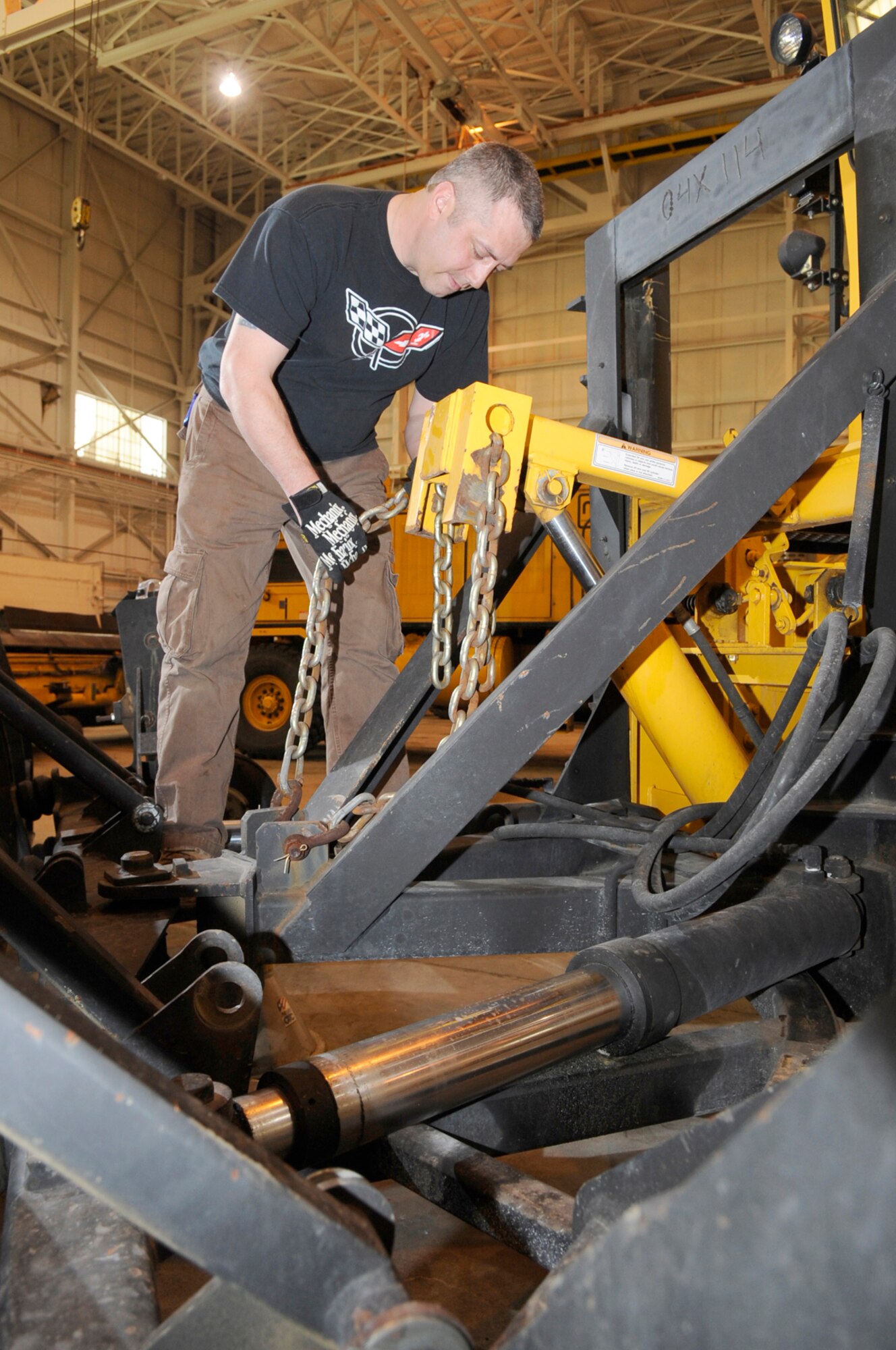Michael Mattay, 87th Civil Engineer Squadron Heavy Equipment Shop operator, adjusts the chain on a hydraulic ram on the front end of a massive 20-ton snowplow March 12. The hydraulic ram raises, lowers, and turns the giant plow head, which can weigh up to 12,000 pounds. The Heavy Equipment Shop recently help save $800,000 by installing a swing gate, which stops deer and other animals from going through a creek onto the base – this reduced the need for extra security to the outer perimeter fence. (U.S. Air Force photo/Carlos Cintron)