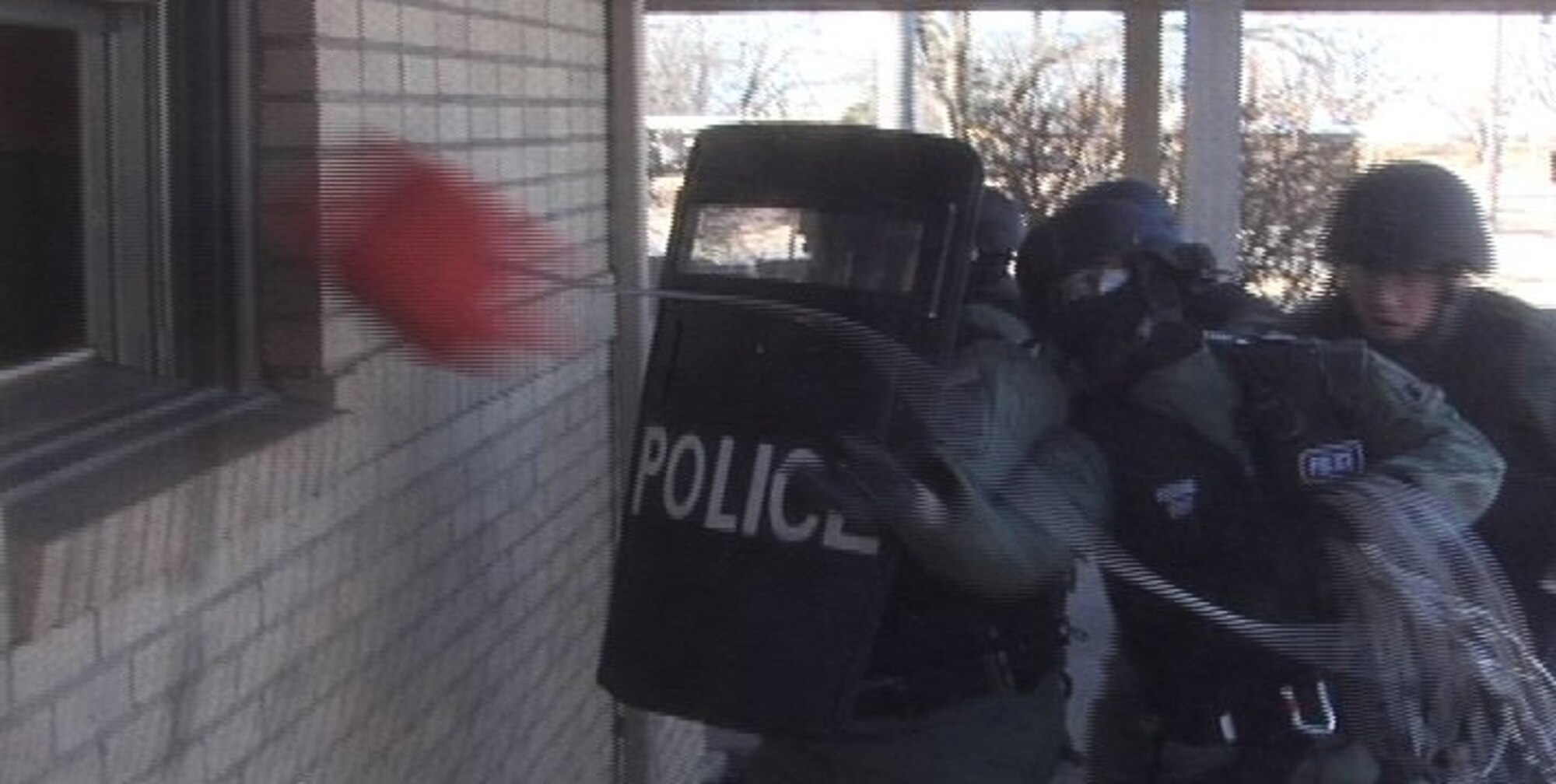 MCCONNELL AIR FORCE BASE, Kan. -- A Team McConnell Emergency Services member throws a box containing a cell phone through a window during a training event in base housing, Feb. 1. The cell phone allows the team a direct line of communication with suspects inside of a building. Communication is the first step employed by the team during a hostage or barricade situation to try and end the situation without the use of force.  (Photo by Senior Airman Nicholas Stowers)