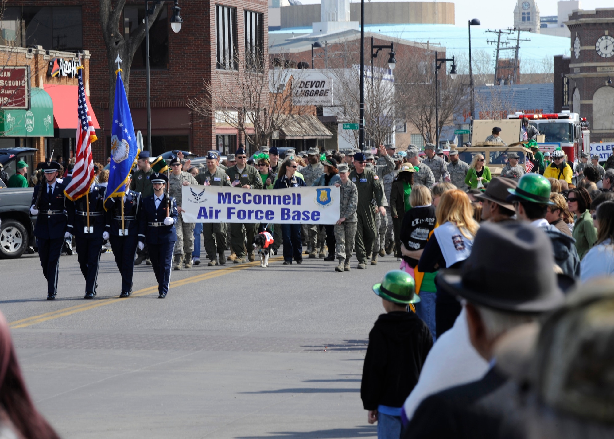 Wichita, Kan. -- Team McConnell members walk down Douglas Street behind a base honor guard detail during Wichita’s St. Patrick’s Day parade, March 13. McConnell was positioned at the front of the parade train and made use of two high mobility multipurpose wheeled vehicles, a float, and a fire truck from the 22nd Civil Engineer Squadron. (Photo by Airman Justin Shelton) 