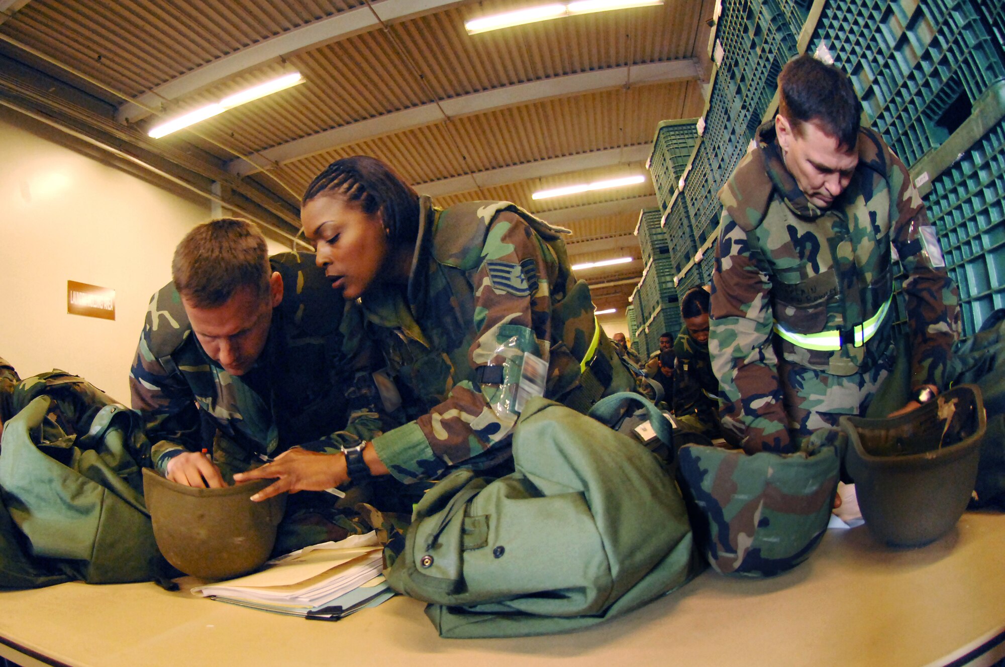 349th Air Mobility Wing members, left to right, Capt. Ryan Jones, Staff Sgt. Stacey JAckson and Maj. Kenneth Rowley take inventory of their deployment bags during the Crisis Look exercise. (U.S. Air Force photo/Amanda Lopez)