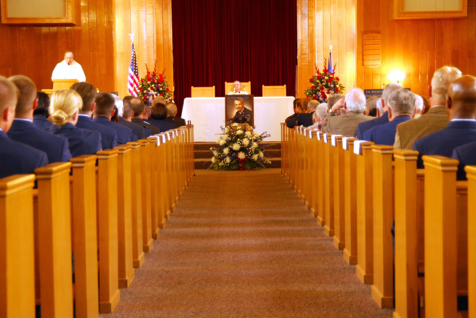 The centerpiece of the memorial service for the first Chief Master Sgt. of the Air Force, Paul W. Airey, rests in the center of the Tyndall Air Force Base chapel sanctuary March 16. In front of the painted portrait of the Chief rested a solitary service cap facing forward to the audience. More than 500 people were in attendance for the memorial service. (U.S. Air Force photo/Susan Trahan)