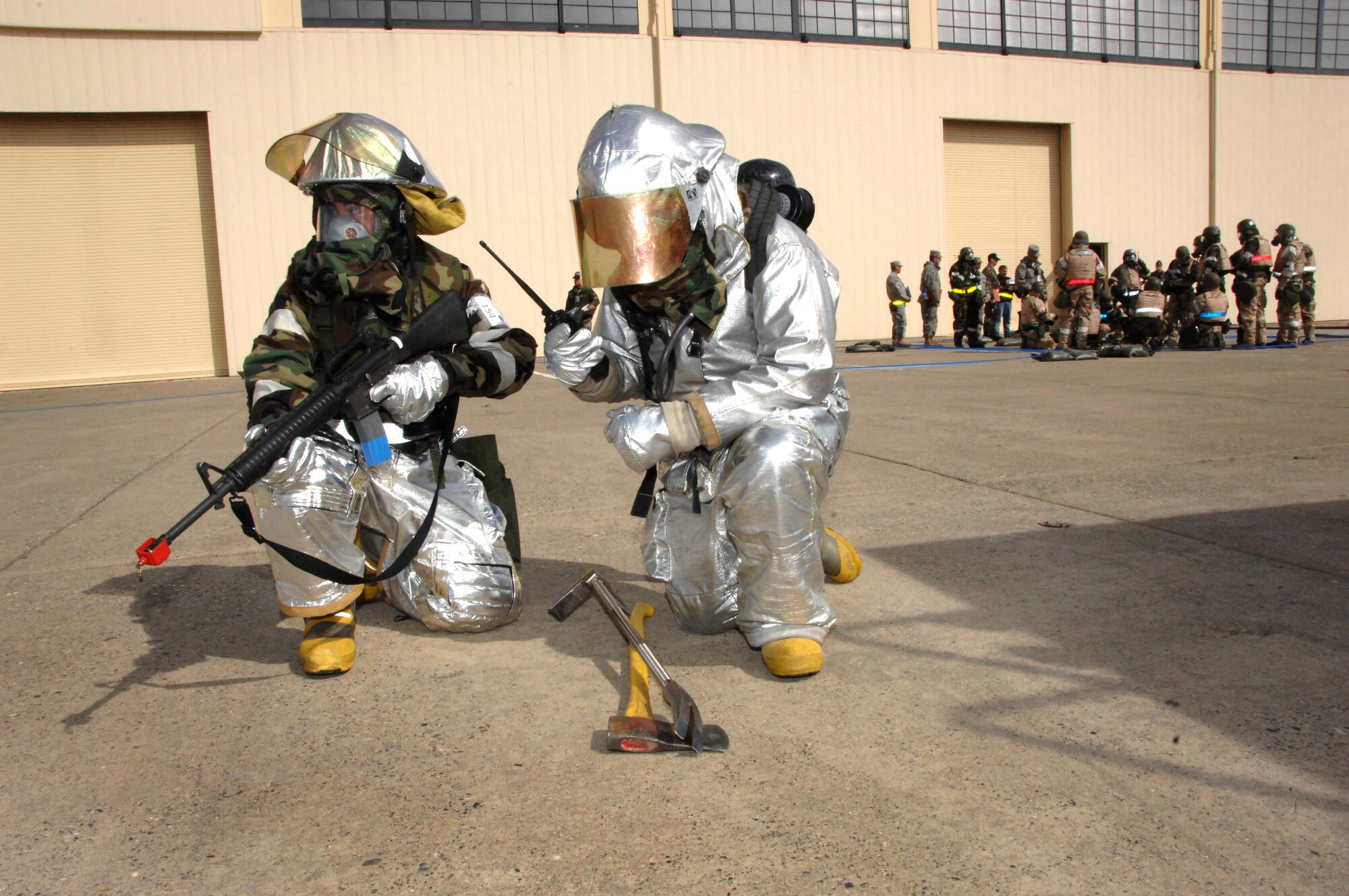 Airman 1st Class Fabian Madrid, left, and Airman 1st Class Brandon Barry, both of the 60th Civil Engineer Squadron, protect the perimeter of the building while other firefighter team members contain the simulated fire during the CRISIS LOOK 09-02 exercise. (U.S. Air Force photo/Amanda Lopez)