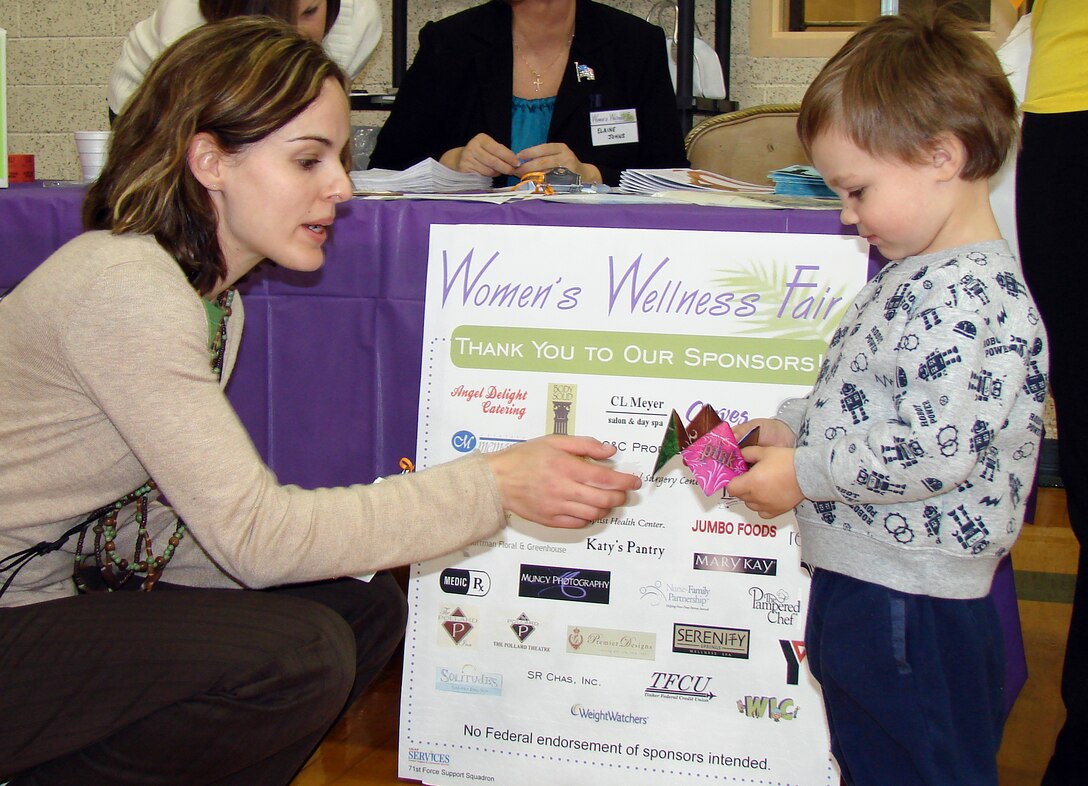 Melissa Seror, publicist for the 71st Force Support Squadron and Services marketing office, helps Adam Call, age 2, with his paper fortune teller at the Women's Wellness Fair Thursday, March 12. (U.S. Air Force photo by 2nd Lt. Lynn Aird)