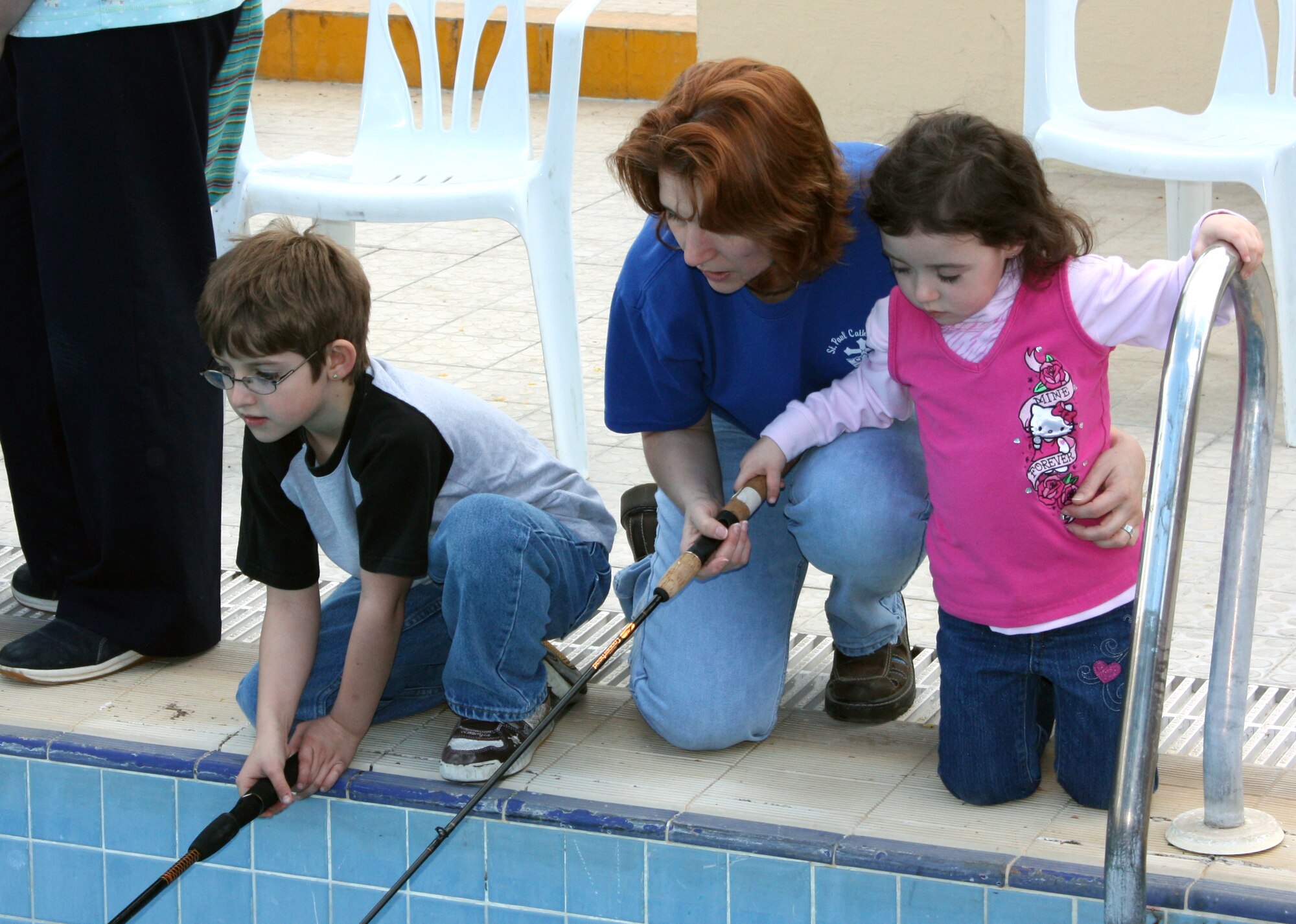 Master Sgt. Melanie Adams, American Forces Network – Incirlik, helps her children Liam and Kieran fish while at the base pool during the Fishing Rodeo March 14. Approximately 400 trout were placed in the pool for the weekend event, giving the Incirlik community a chance to catch their dinner. The pool was drained and cleaned before and after the event. (U.S. Air Force photo/Staff Sgt. Chris Galindo)