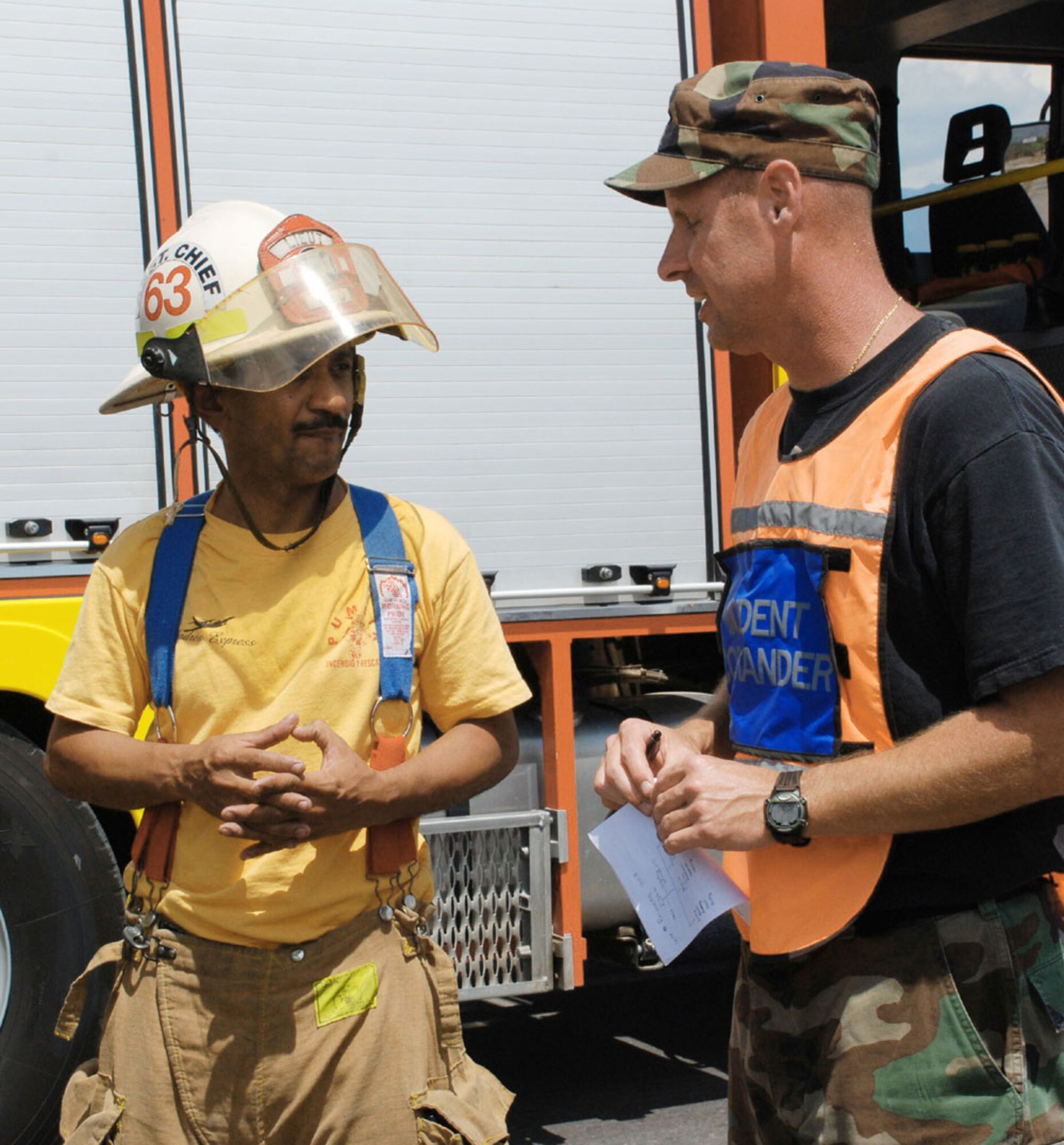 Master Sgt. Pat Miller consults with Comayagua Deputy Fire Chief Lt. Jorge Turcias on a plan to safely recover an overturned fuel truck March 13 8 kilometers north of Soto Cano Air Base, Honduras. The truck overturned approximately 8 kilometers north of the base after hitting a horse around 8 a.m. Sergeant Miller is a Joint Task Force-Bravo firefighter stationed at Soto Cano AB. (U.S. Air Force photo/Tech. Sgt. Rebecca Danet) 
