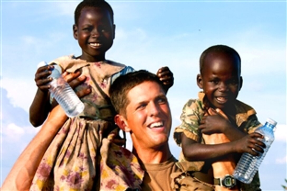 U.S. Navy Petty Officer 2nd Class Peter A. Belcastro gives local children a ride on his shoulders at the end of his day's work in Aromo, Uganda, March 3, 2009. Belcastro is assigned to Naval Mobile Construction Battalion 11, which is assigned to Combined Joint Task Force Horn of Africa in its first deployment since being re-established in 2007.