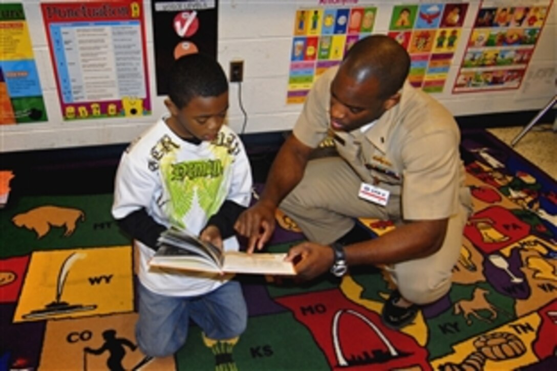 A student reads to Navy Lt. jg David Ngbea, systems training officer for Amphibious Squadron 8, March 12, 2009, during a community outreach project at Pembroke Elementary School. Sailors assigned to PHIBRON 8 visited the school as part of a continuous community outreach and educational program.