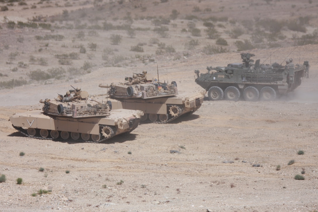 Tanks with Company C, 1st Tank Battalion, and a stryker with 1st Battalion, 23rd Infantry Regiment, watch the mock town below them as other U.S. soldiers and tanks storm the town during a side-by-side integration exercise at the Combat Center March 18.