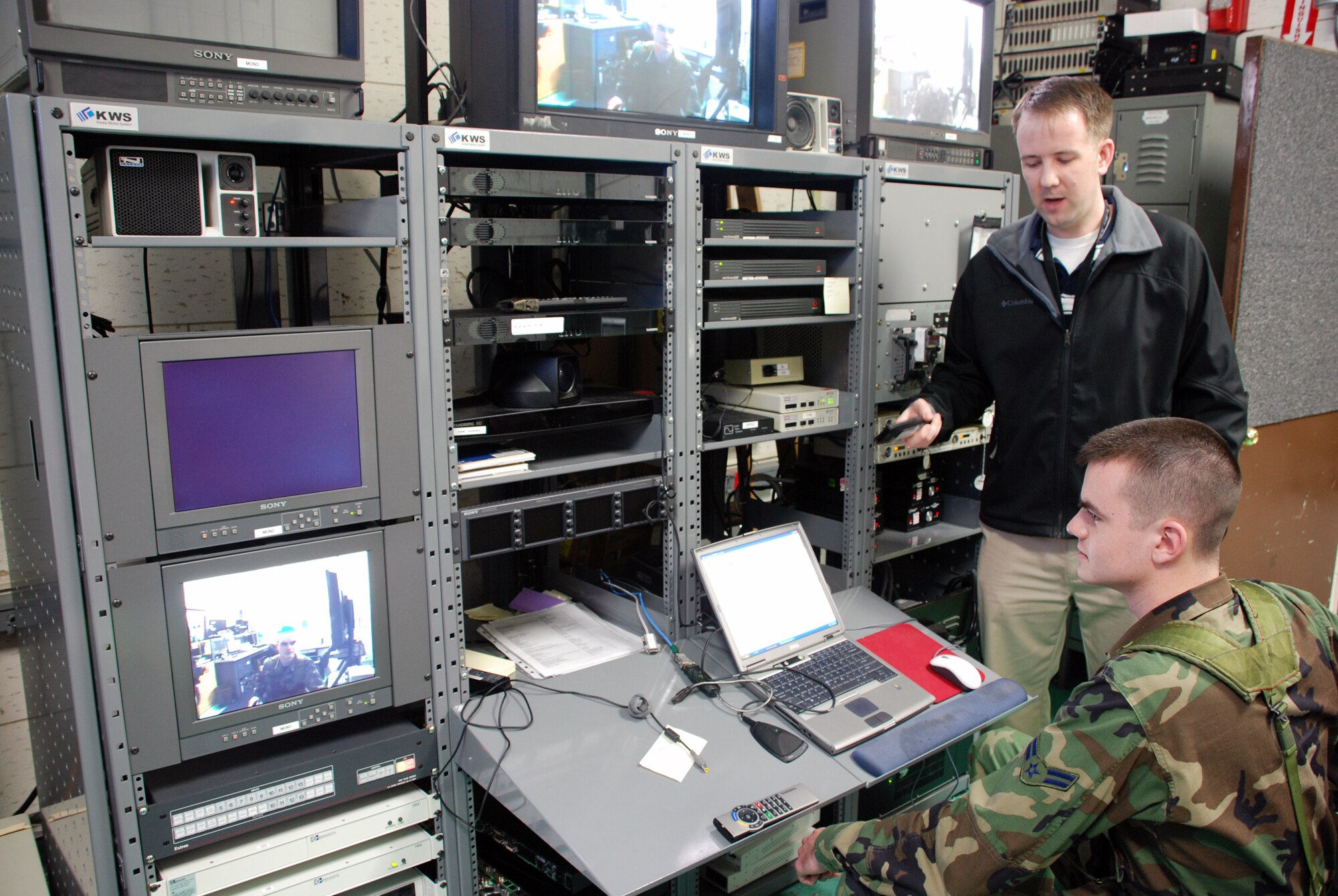 Forest Shanahan, 607th Air & Space Communications Squadron audio visual engineer, explains the Hardened Tactical Air Control Center video conferencing system to Airman 1st Class Dana MacMillan, 607th Air Communications Squadron augmentee, March 18 in the Hardened Tactical Air Control Center. Airman MacMillan is deployed from Whiteman AFB, Mo., where he works for the 509th Communications Squadron on visual imagery and intrusion detection systems. The 607 ACOMS is responsible for fielding new and ensuring current communications are available to allow the supporting weapon system divisions to provide their products to Combat Operations to execute the Air Tasking Order. (USAF photo by Staff Sgt. Alex Saltekoff)