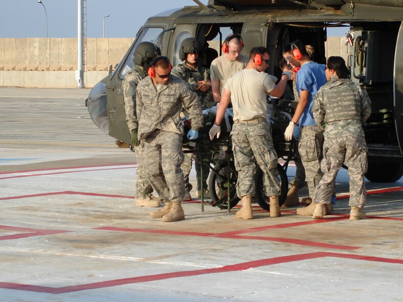 JOINT BASE BALAD, Iraq -- Tech. Sgt. Christopher Mendonca, 35th Maintenance Squadron electronic warfare systems section producer, grabs the end of a patient litter on the helo-pad, unloading a medical evacuation patient who was hit by an improvised explosive device, Oct. 26, 2008. During his deployment to Iraq from September 2008 to February, Sergeant Mendonca volunteered nearly 300 hours helping injured coalition members at the hospital. (Courtesy photo) 