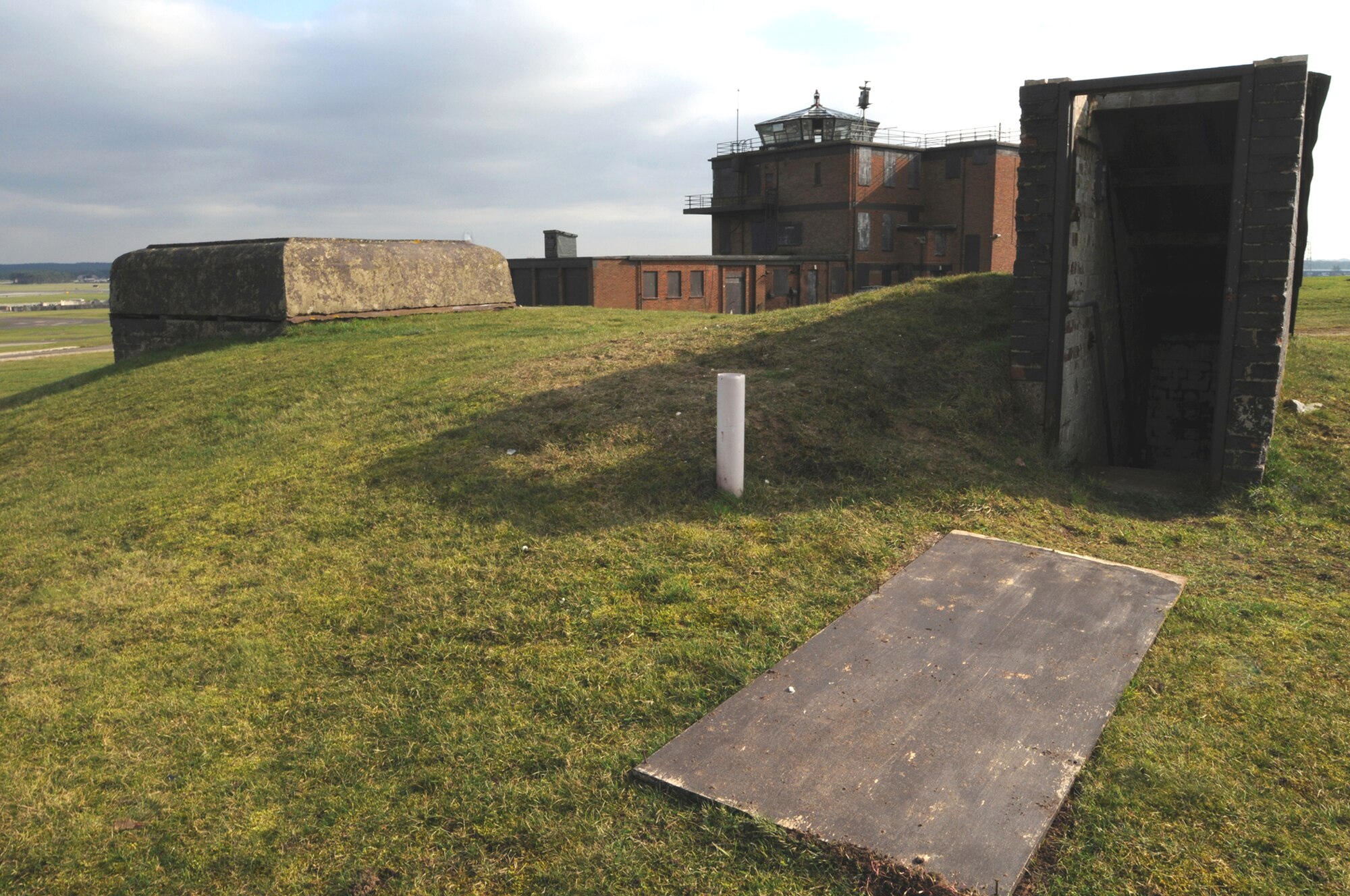 Two structures from two different eras sit next to each other near the RAF Lakenheath flightline Feb. 27. The command bunker in the foreground was used by commanders during World War II to defend the airfield against German Paratroopers. The control tower in the background is a relic of the Cold War Era and was used from 1948 through 1992, it's scheduled to be demolished. (U.S. Air Force photo/Staff Sgt. Nathan Gallahan) 