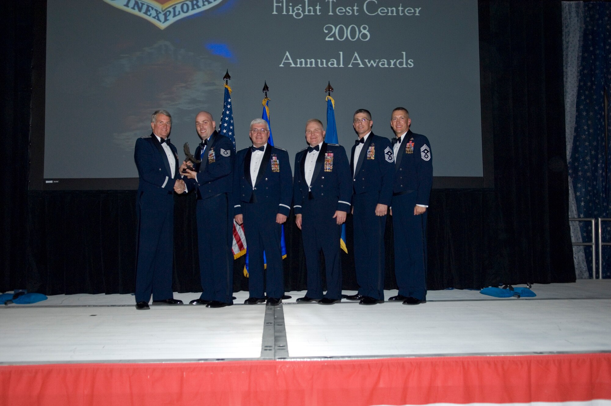 Tech. Sgt. Daniel Halverstadt (second from left), 412th Operations Group evaluator loadmaster, received the Air Force Flight Test Center Noncommissioned Officer of the Year from Maj. Gen. David Eichhorn (left), AFFTC commander, during a ceremony at Hangar 1820 March 13. (U.S. Air Force photo/Mike Cassidy)