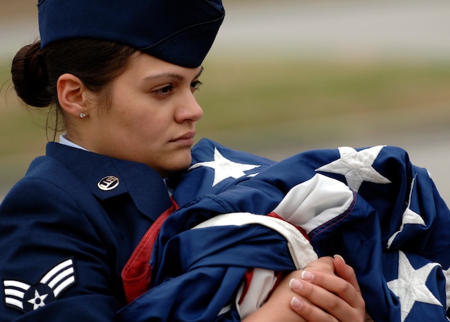 Senior Airman Nicole Moreira embraces the flag after lowering it during the all-women retreat ceremony here March 13. National Women's History Month recognizes the accomplishments of women in America. Airman Moreira is a vehicle maintenance controller for the 437th Logistics Readiness Squadron. (U.S. Air Force photo/Senior Airman Timothy Taylor)