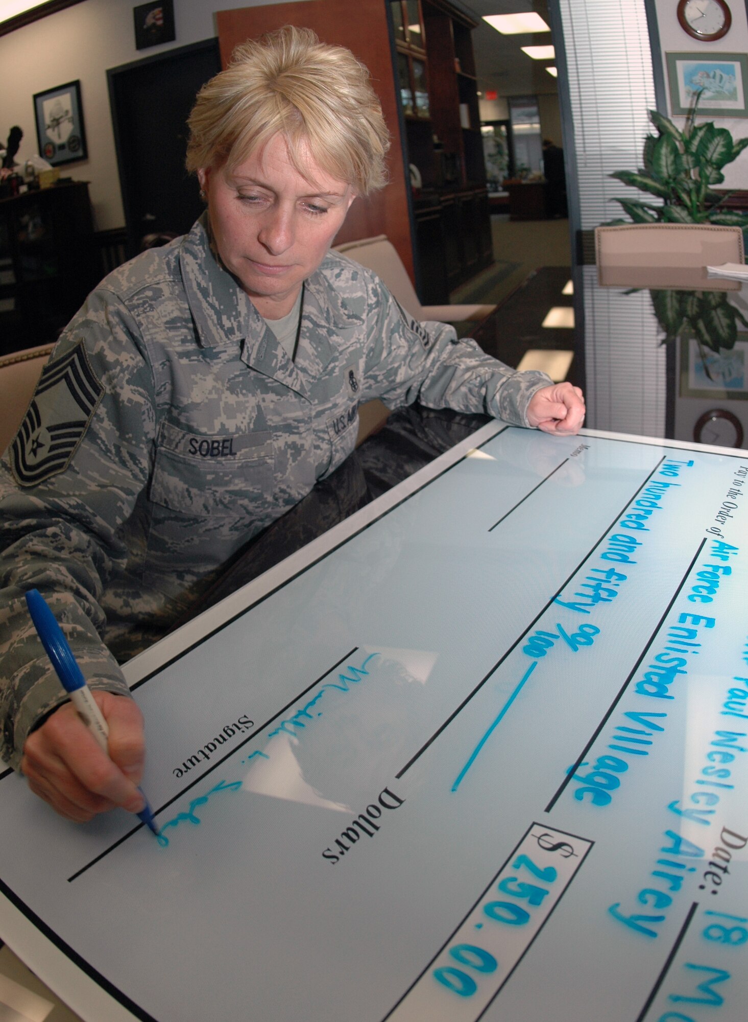 Chief Master Sgt. Michelle Sobel, Travis Chief's Group vice president makes out a check for a $250 dontation to the Air Force Enlisted Village. The dontation is in support of the Air Force Assistance Fund campaign which runs until April 20. (U.S. Air Force photo/Staff Sgt. Shaun Emery)