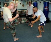 Master Sgt. William "Joe" Stapp (left), 919th Security Forces Squadron, and Master Sgt. Paul Morales (right), 919th SFS first sergeant, demonstrate a front kick during a weekly Krav Maga training class. Sergeants Stapp and Morales are certified instructors in Krav Maga, which is a type of close-quarters combat training developed in Israel and used by Israeli Defense Forces as well as several U.S. government and law enforcement agencies. Rigorous training routines help students build greater cardio fitness, muscle strength and coordination, as well as provide strong self defense tactics for real world or combat situations. (U.S. Air Force photo / Senior Airman Jon McCallum)