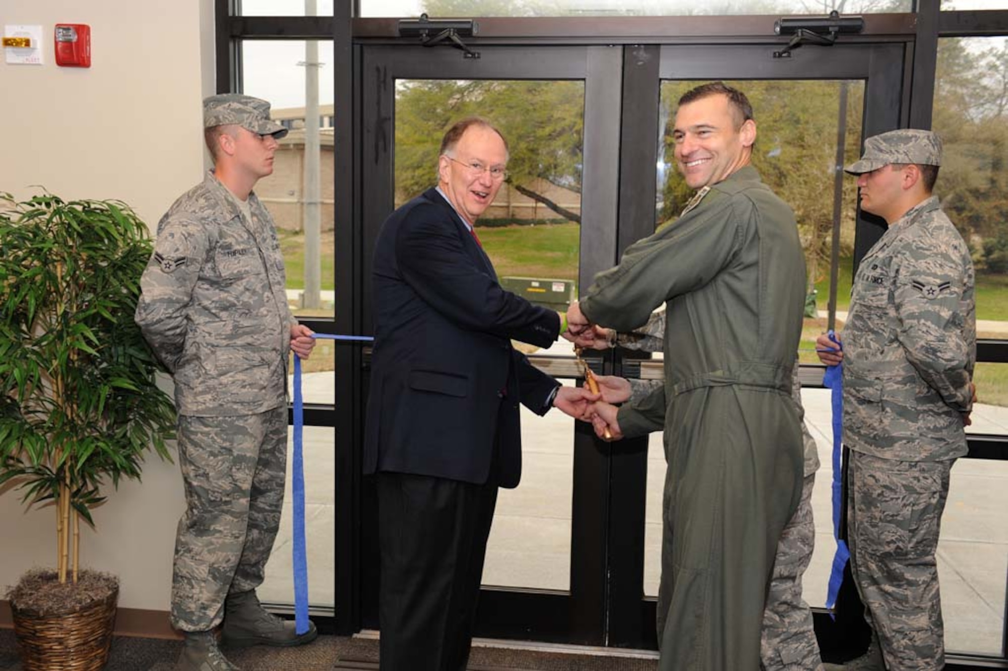 SHAW AIR FORCE BASE, S.C. -- Col. Joseph Guastella, 20th Fighter Wing commander, the Sumter Mayor, Joseph McElveen and Airman 1st Class Lisa Riendeau, 20th Logistics Readiness Squadron, do the honors of cutting the ribbon to open Shaw's new dorms March 13. The suites in the new dorm consist of a common area with a full kitchen, living room, laundry room and four private bedrooms. Each bedroom is equipped with a private bathroom and a walk-in closet. The new dormitory has space for 144 occupants. (U.S. Air Force photo/Senior Airman Matthew Davis)