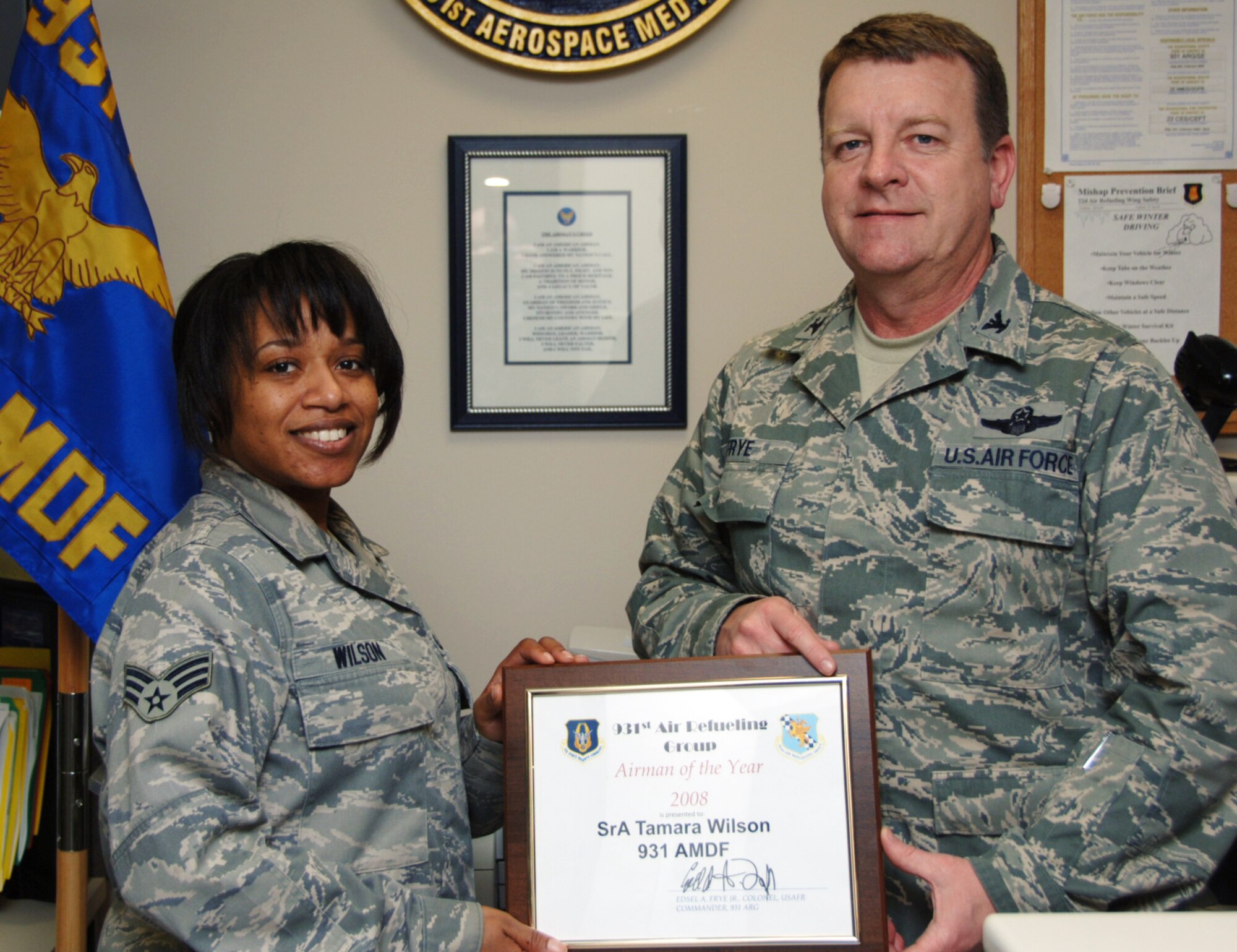 Col. Edsel A. "Archie" Frye Jr. presents the Airman of the Year award to Senior Airman Tamara Wilson on March 17. Airman Wilson, a public health technician assigned to the 931st Aerospace Medicine Flight, was not in attendance when her award was announced a few days prior during a commander's call. Colonel Frye is the commander of the 931st Air Refueling Group, an Air Force Reserve unit at McConnell Air Force Base, Kan. The month of March was declared Women's History Month to recognize the contributions of women like Airman Wilson. (U.S. Air Force photo/Tech. Sgt. Jason Schaap)