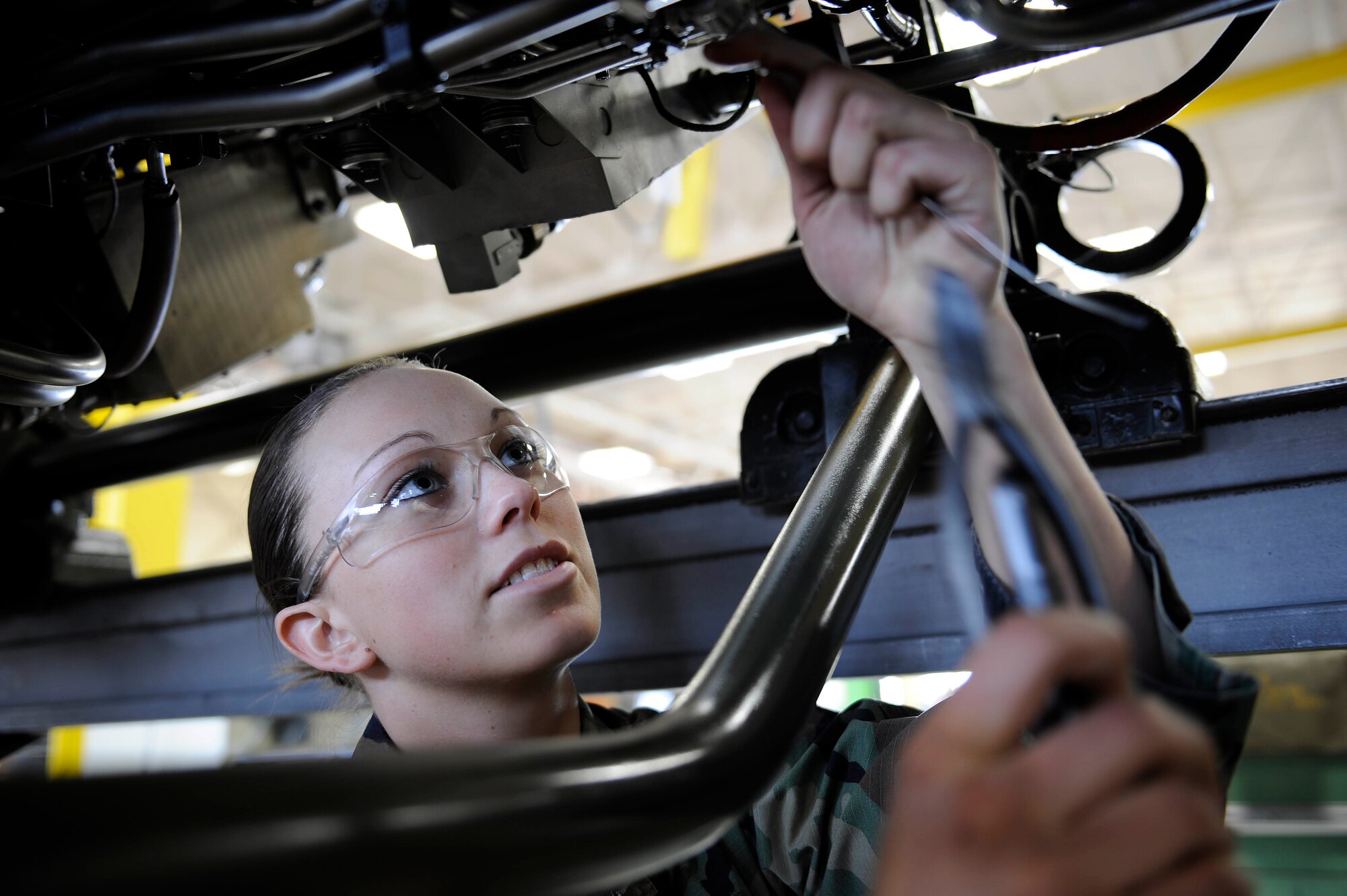 Senior Airman Angelique Hasz, 28th Maintenance Squadron aerospace propulsion journeyman, connects safety wire to fuel, brake and oil lines underneath a B-1B Lancer's General Electric F101 turbofan engine here, March 17. Airman Hasz is one of three women working in the propulsion backshop. Since 1987, the month of March has been recognized as Women's History Month and highlights women of the past and future. (U.S. Air Force photo by Airman 1st Class Corey Hook)