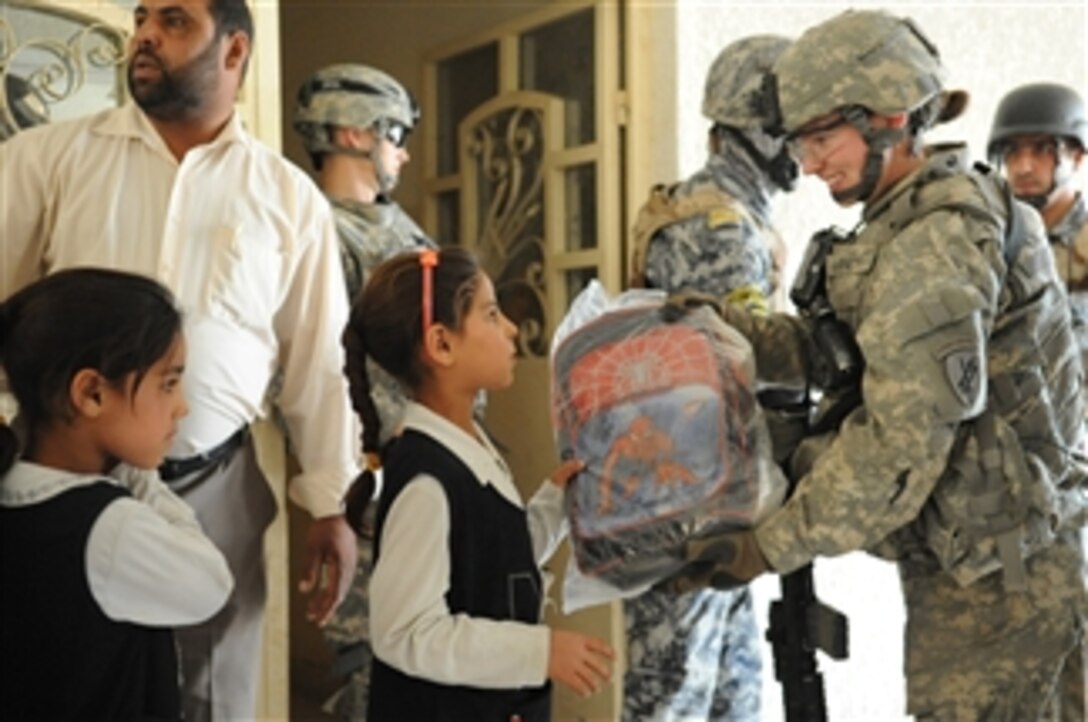 U.S. Army Sgt. Sheena Barnett of Bravo Company, 401st Civil Affairs Battalion gives an Iraqi schoolgirl a new book bag at Shawra Wa Um Jidir in eastern Baghdad, Iraq, on March 8, 2009.  Iraqi National police and U.S. soldiers are visiting local schools and distributing school supplies.  