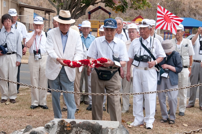 Former Japanese Imperial Navy Lt. j.g. Kaname Harada (blue cap) places a carnation lei on a memorial to fallen Japanese pilot Lt. Fusata Iida during his visit to Marine Corps Base Hawaii June 3. Harada toured the base with several members of the Unabarakai Association of Tokyo, comprised of surviving Japanese Zero fighter pilots.