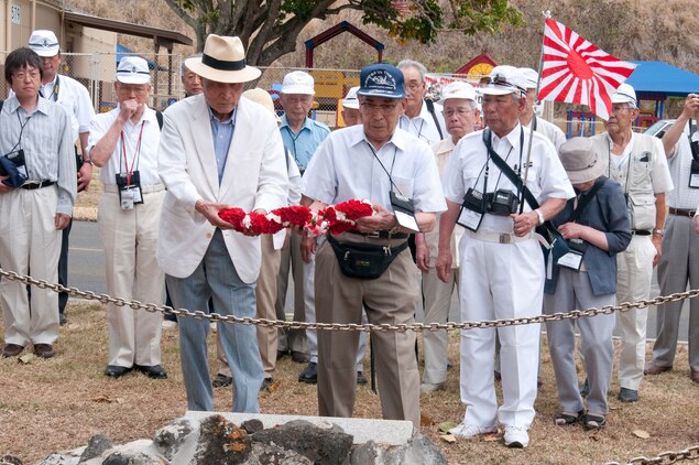 Former Japanese Imperial Navy Lt. j.g. Kaname Harada (blue cap) places a carnation lei on a memorial to fallen Japanese pilot Lt. Fusata Iida during his visit to Marine Corps Base Hawaii June 3. Harada toured the base with several members of the Unabarakai Association of Tokyo, comprised of surviving Japanese Zero fighter pilots.