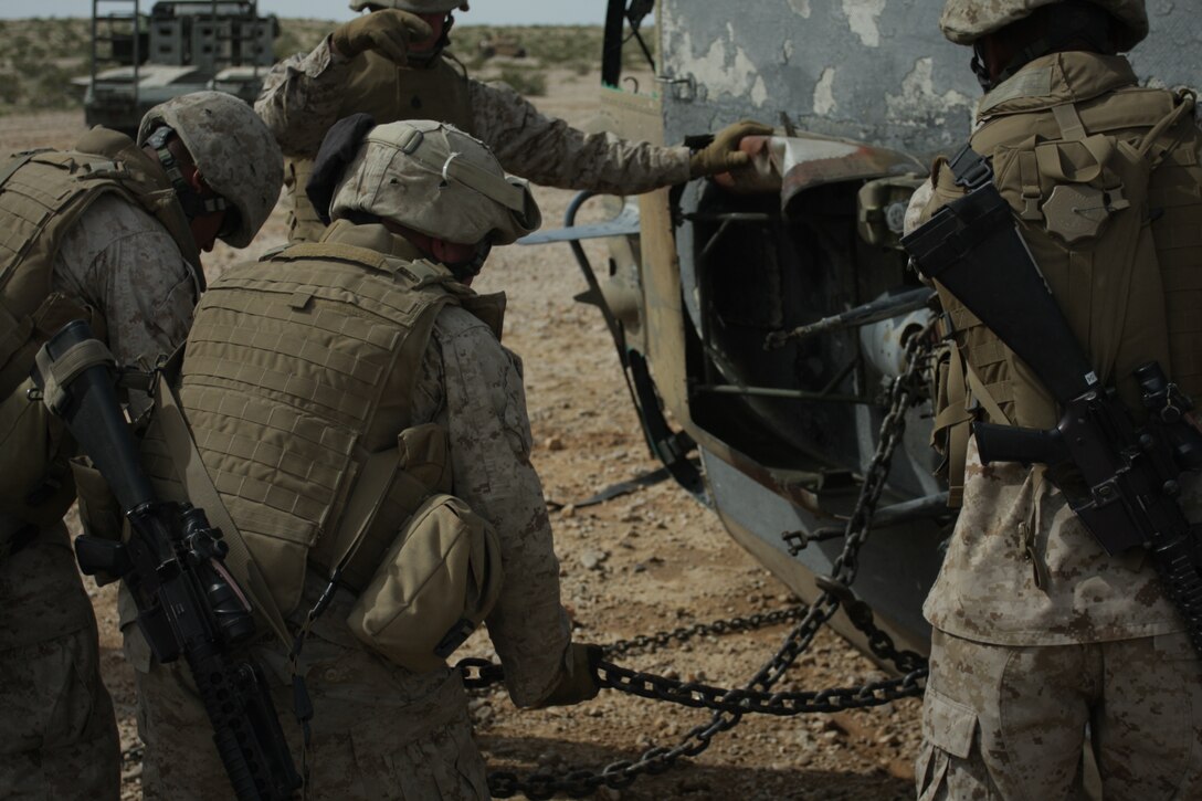 Marines from the Marine Wing Support Squadron 374 aircraft recovery team secure chains to the top of a helicopter hulk so it can be lifted by a wrecker vehicle during a mock Tactical Recovery of Aircraft and Personnel mission March 19. The TRAP mission was part of a week-long field operation to prepare the Marines and sailors of MWSS-374 for combat operations overseas.