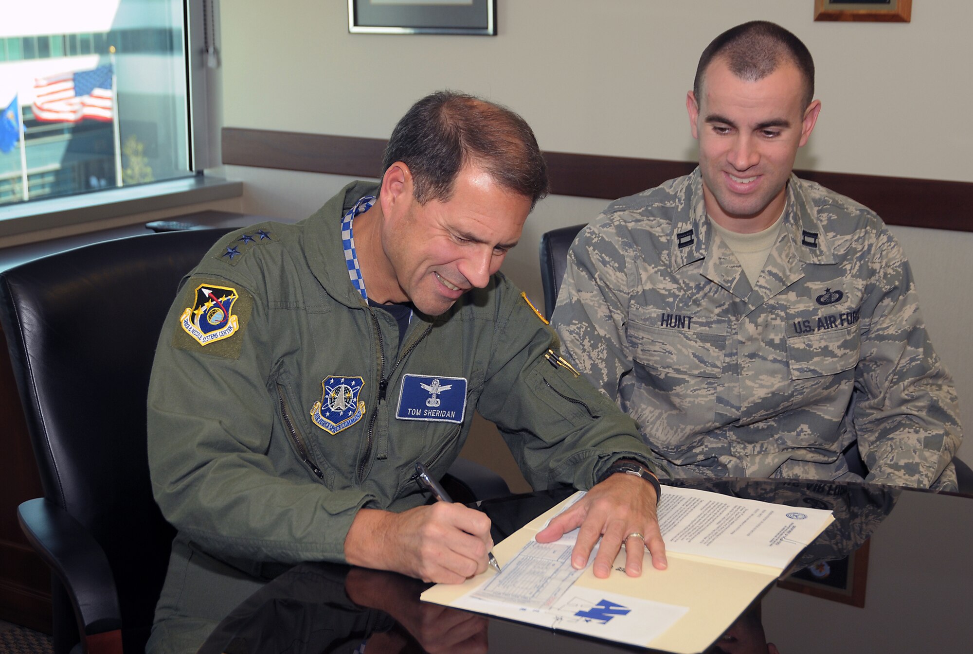 SMC Commander Lt. Gen. Tom Sheridan signs a pledge form for this year’s Air Force Assistance Fund Campaign as Capt. Shaun Hunt looks on. This year’s campaign runs March 9 through April 17. Airmen can donate through their individual unit representatives. (Photo by Joe Juarez)