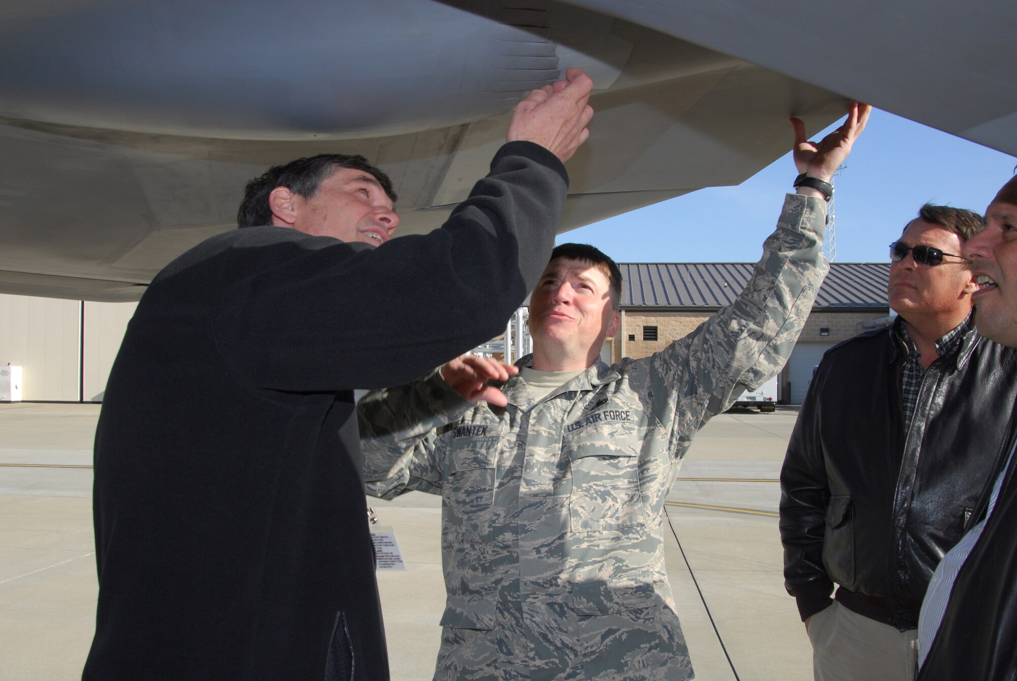 Above, An Airman from the 43rd Fighter Squadron, Tyndall Air Force Base, Fla., gives Henry Lowe (left), Lowe Aviation president, a closer look at  the underbelly of an F-22 Raptor, while Lee Minor, Appraisal Service, looks on. U. S. Air Force courtesy photo
