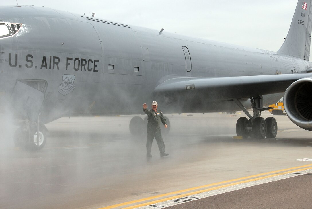 Col. William E. Anderson waves hello after getting doused with a fire hose upon returning from his final flight as outgoing commander of the 161st ARW.