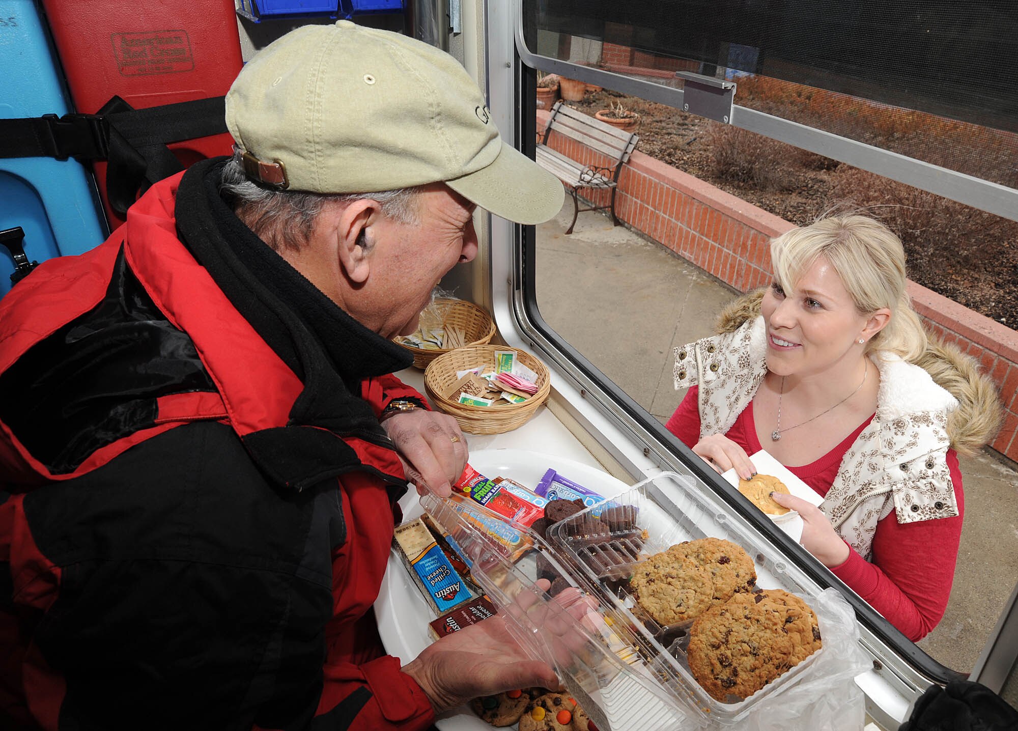 Despite the frigid temperature and freezing rain, American Red Cross volunteers, Vince Azzinaro hands Sarah Anderson a cookie and hot chocolate. Mr. Azzinaro was handing out goodies to shoppers on March 14. (U.S. Air Force photo/Staff Sgt. JT May III)