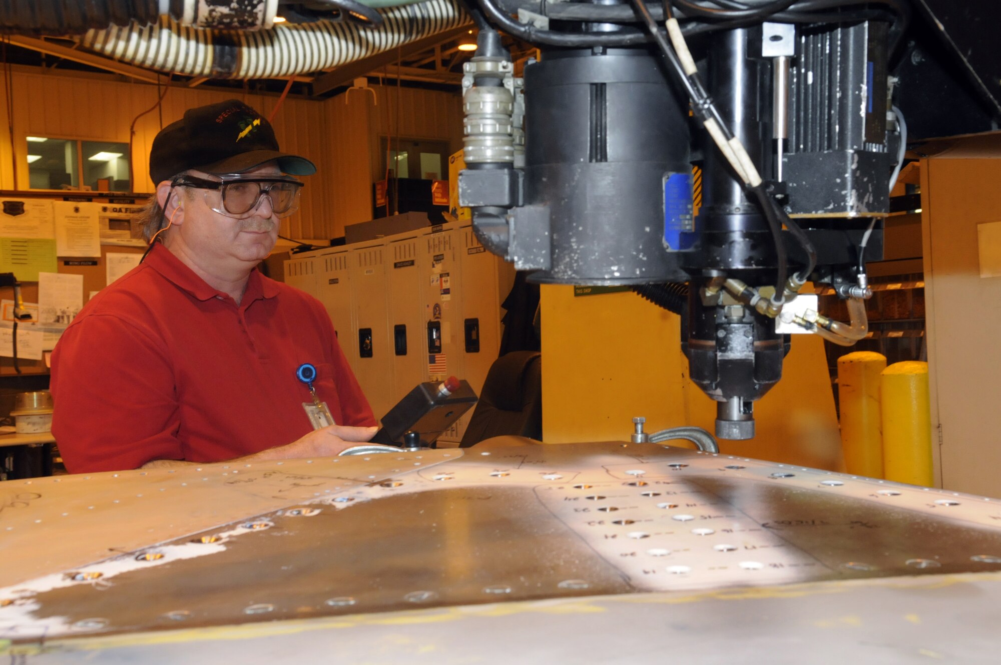 Charles Confer, sheet metal mechanic and robot operator, controls the robot away from the computer console with a hand-held teach pendant. U. S. Air Force photo by Sue Sapp