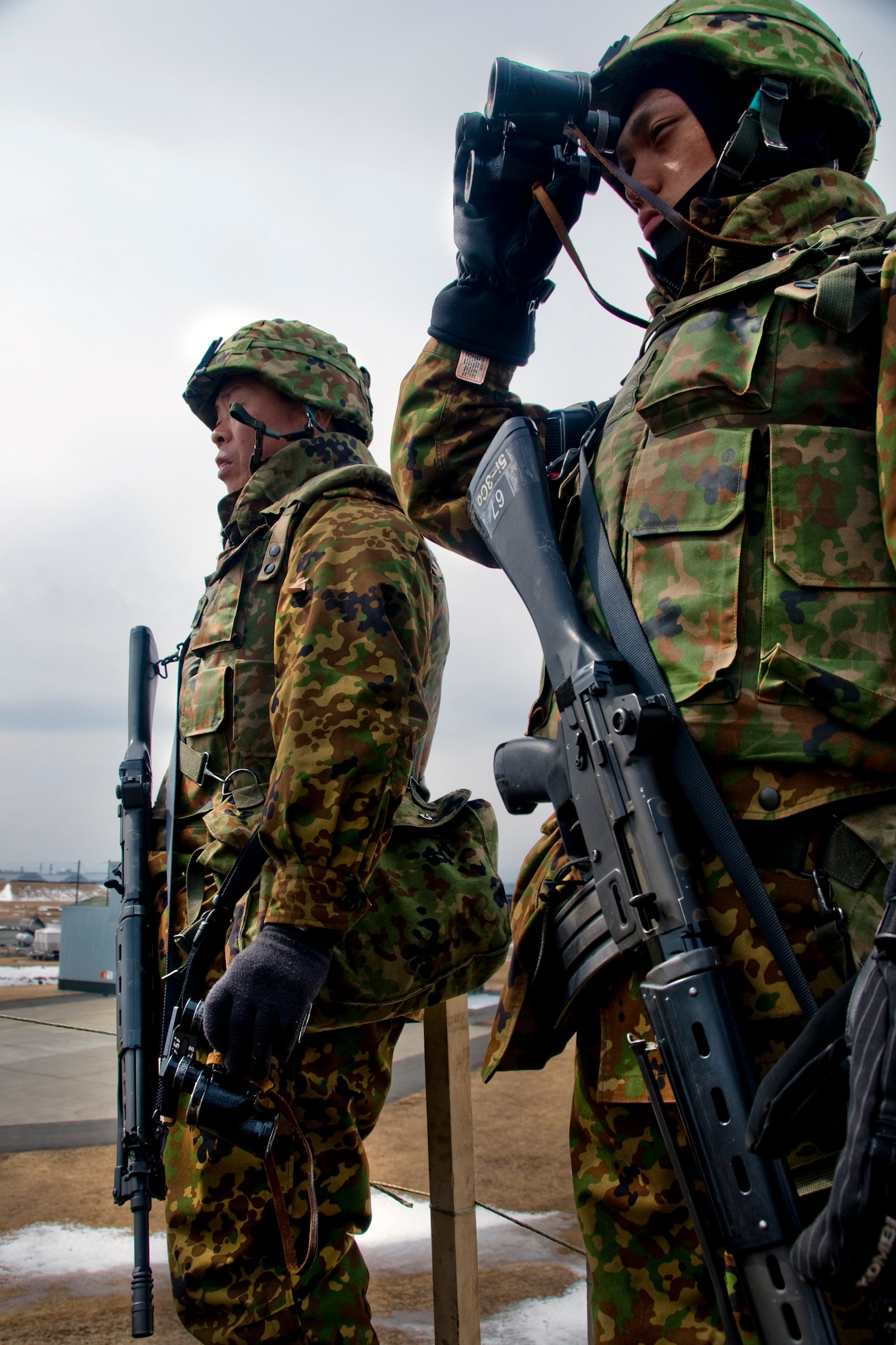 Two members of the Japan Ground Self-Defense Force 9th Division, 5th Infantry Regiment, watch over a specified area during a March 13 exercise at Misawa Air Base, Japan. The JGSDF troops were part of a 24-hour Guard and Protect Exercise that partnered them with the Japan Air Self-Defense Force 3rd Air Wing and the U.S. Air Force 35th Security Forces Squadron. (U.S. Air Force photo/Senior Airman Jamal D. Sutter) 
