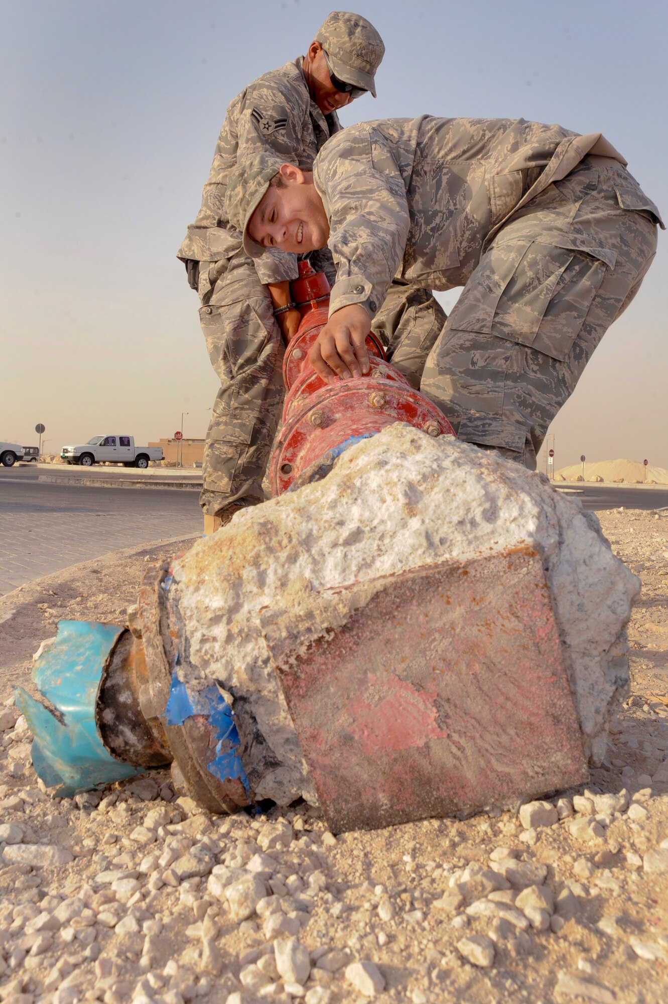 Airman 1st Class Ryan Schmutzler and Airman 1st Class Frank Payton, both Zone Utilities Journeymen with the 379th Expeditionary Civil Engineer Squadron, drag a fire hydrant out of the way to repair a broken water line here, Mar. 18, 2009, in an undisclosed location in Southwest Asia.  The Zone Utilities shop handles all water and plumbing issues in the housing areas around the base.  Airman Schmultzler is native to Alanta, Ga. and is deployed from Fairchild Air Force Base, Wash. and Airman Payton is native to San Antonio, Texas and is deployed from Eilson Air Force Base, Alaska in support of Operations Iraqi and Enduring Freedom and Combined Joint Task Force - Horn of Africa.  (U.S. Air Force Photo by Staff Sgt. Joshua Garcia/released)