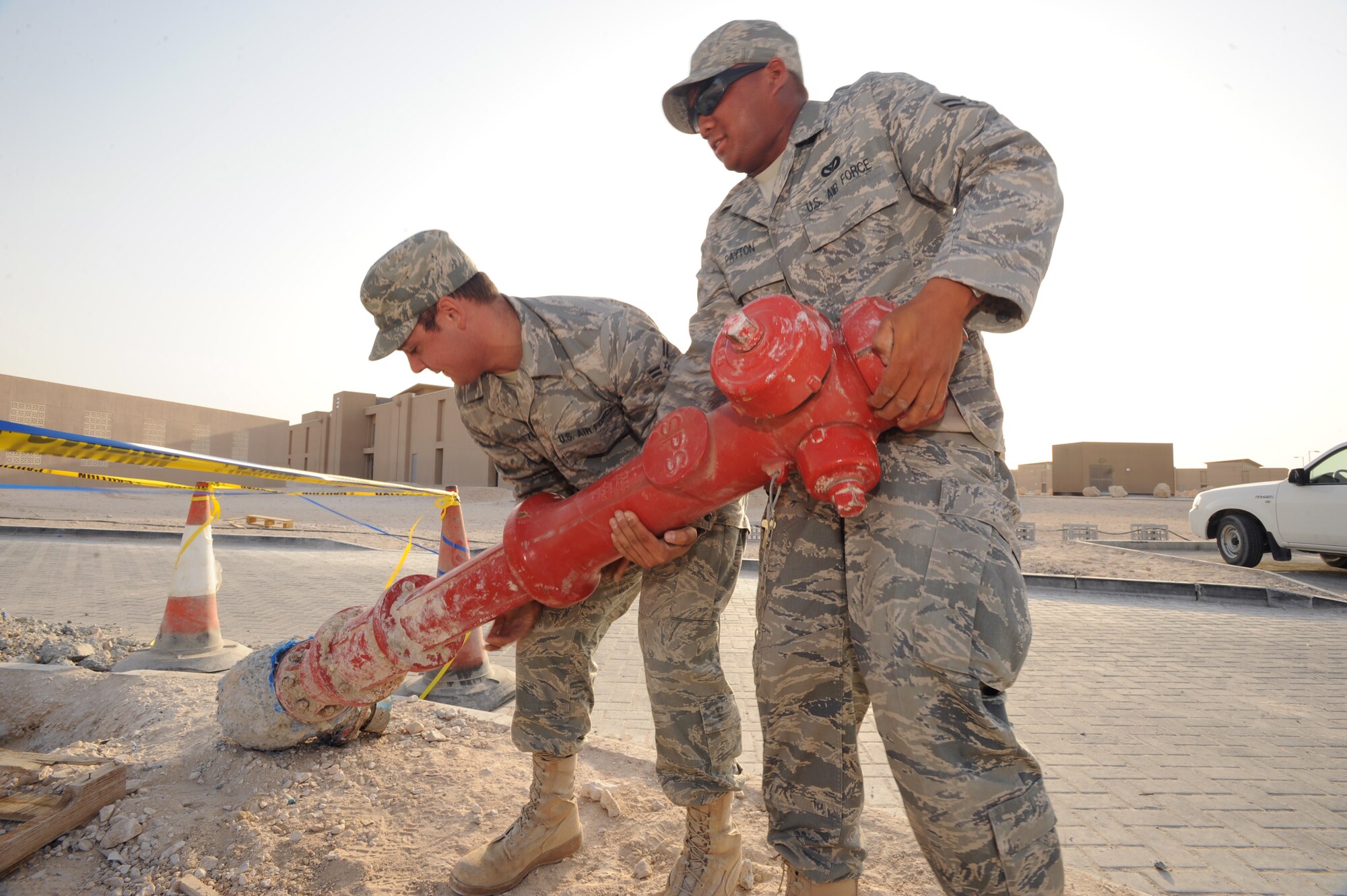 Airman 1st Class Ryan Schmutzler and Airman 1st Class Frank Payton, both Zone Utilities Journeymen with the 379th Expeditionary Civil Engineer Squadron, drag a fire hydrant out of the way to repair a broken water line here, Mar. 18, 2009, in an undisclosed location in Southwest Asia.  The Zone Utilities shop handles all water and plumbing issues in the housing areas around the base.  Airman Schmultzler is native to Alanta, Ga. and is deployed from Fairchild Air Force Base, Wash. and Airman Payton is native to San Antonio, Texas and is deployed from Eilson Air Force Base, Alaska in support of Operations Iraqi and Enduring Freedom and Combined Joint Task Force - Horn of Africa.  (U.S. Air Force Photo by Staff Sgt. Joshua Garcia/released)