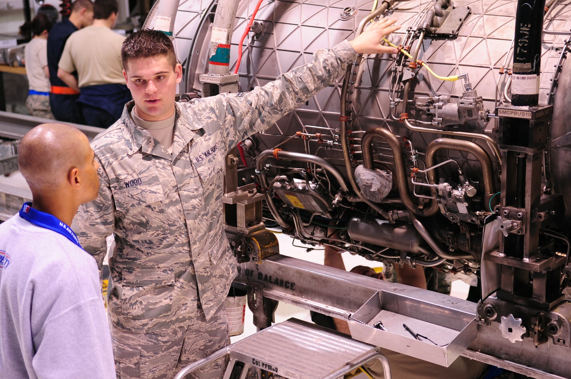 Airman 1st Class Kenneth Wood, 4th Component Maintenance Squadron, explains how to remove an oil cooler for the F-15E Strike Eagle’s jet engine to David Cropps, a mechnic from Richard Petty Motorsports, while being filmed for an Air Force recruiting video at Seymour Johnson Air Force Base, N.C., March 11, 2009. The video will show the parallels between Air Force and NASCAR jobs. (U.S. Air Force photo by Airman 1st Class Rae Perry)