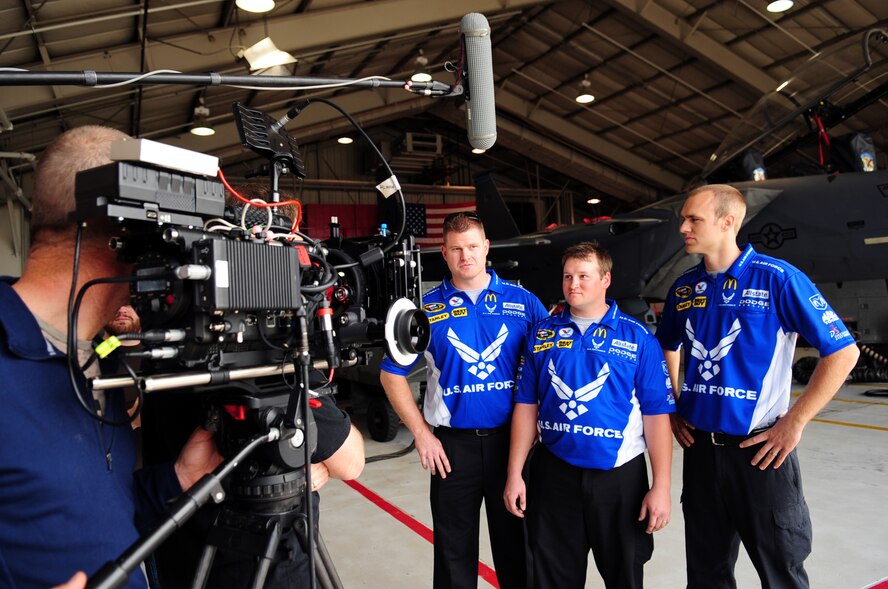 Ed Watkins, Brett Morrell and Bryan Jacobsen, NASCAR Sprint Cup 43 Air Force car crew, explain what it is like to change a tire on an F-15E Strike Eagle at Seymour Johnson Air Force Base, N.C., March 11, 2009. The Air Force Recruiting Service filmed the mechanics from Richard Petty Motorsports as they interacted with 4th Fighter Wing aircraft maintainers as part of an Air Force recruiting video that shows the similarities between NASCAR and Air Force employment. (U.S. Air Force photo by Airman 1st Class Rae Perry)