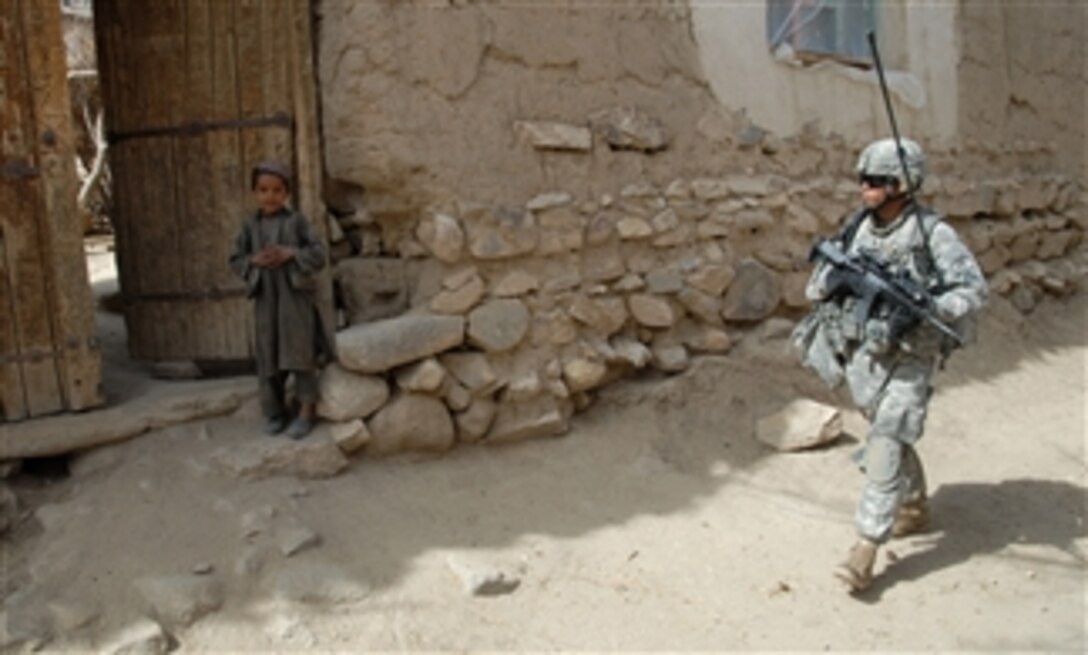 U.S. Army 1st Lt. Jason Basilides, platoon leader, 2nd Platoon, Bravo Company, 1st Battalion, 4th Infantry Regiment, U.S. Army Europe, walks past a local boy while on a dismounted patrol mission near Forward Operating Base Baylough, Zabul, Afghanistan, on March 17, 2009.  