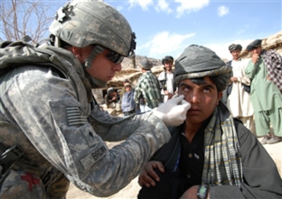 U.S. Army Spc. Chad Brown, a medic assigned to Bravo Company, 1st Battalion, 4th Infantry Regiment, U.S. Army Europe, tends to an Afghan teenager's injured face in a village near Forward Operating Base Baylough in the Zabul province of Afghanistan on March 17, 2009.  