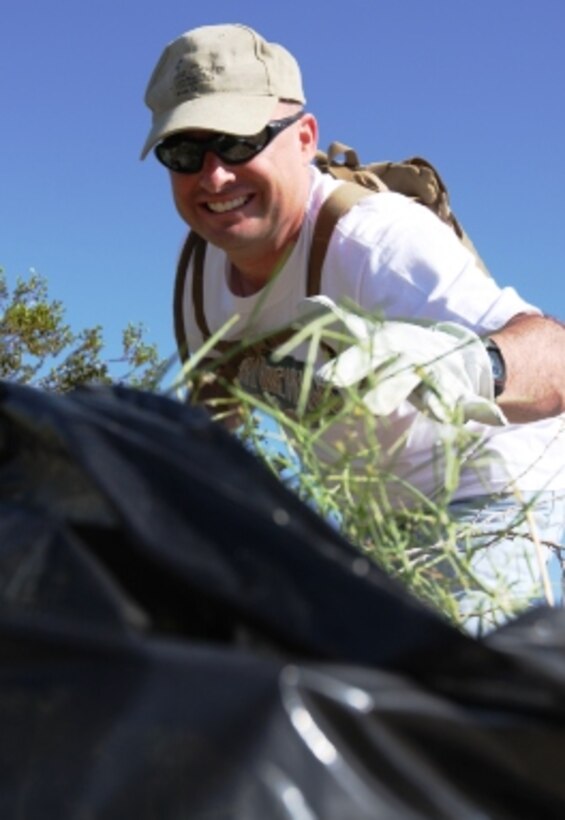 Sgt. Martin Irons, a quality assurance representative for VMU-1, puts a Sahara mustard plant in his trash bag during the unit’s community service project at Joshua Tree National Park, Calif., March 20.
