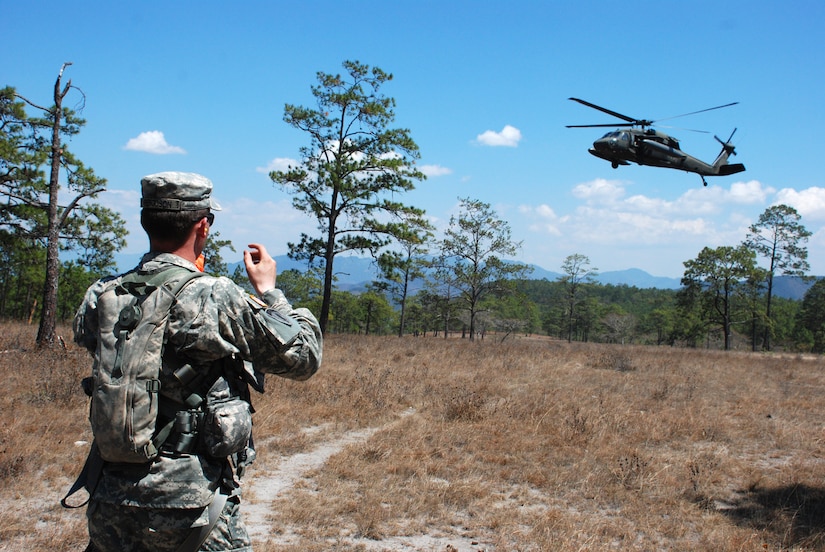 U.S. Army Specialist James Ferguson signals to a HH-60 Blackhawk helicopter as it prepares to land and extract aircrew members during an exercise near La Paz, Honduras, March 20. Eighteen members of the 1st Battalion, 228th Aviation Regiment, assigned to Joint Task Force-Bravo here, took part in the day-long training exercise. The training sharpened land navigation, communication equipment, and aircraft vectoring skills. (U.S. Air Force photo/Tech. Sgt. Mike Hammond)