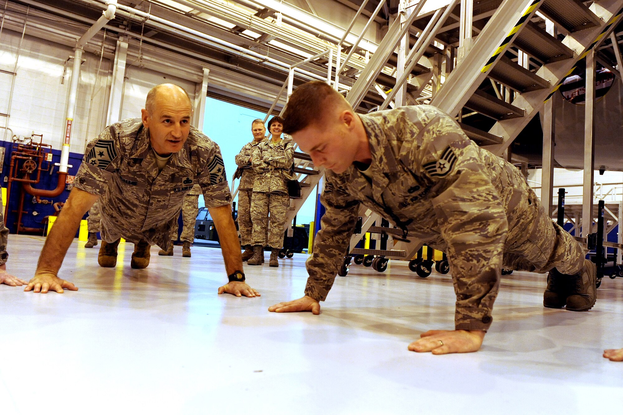 OFFUTT AIR FORCE BASE, Neb. -- ACC Command Chief Master Sgt. Stephen C. Sullens challenges Staff Sgt. Bernie Rowe, 55th Maintenance Squadron, to do 30 pushups with him after stressing the importance of physical fitness for Airman, inside of Dock Three of the Bennie Davis Maintenance Facility, Mar 19. The Chief Sullens toured various facilities as part of a two day base visit to get better acquainted with both the mission and Airmen of the "Fighting Fifty-Fifth."
U.S. Air Force Photo by Josh Plueger
