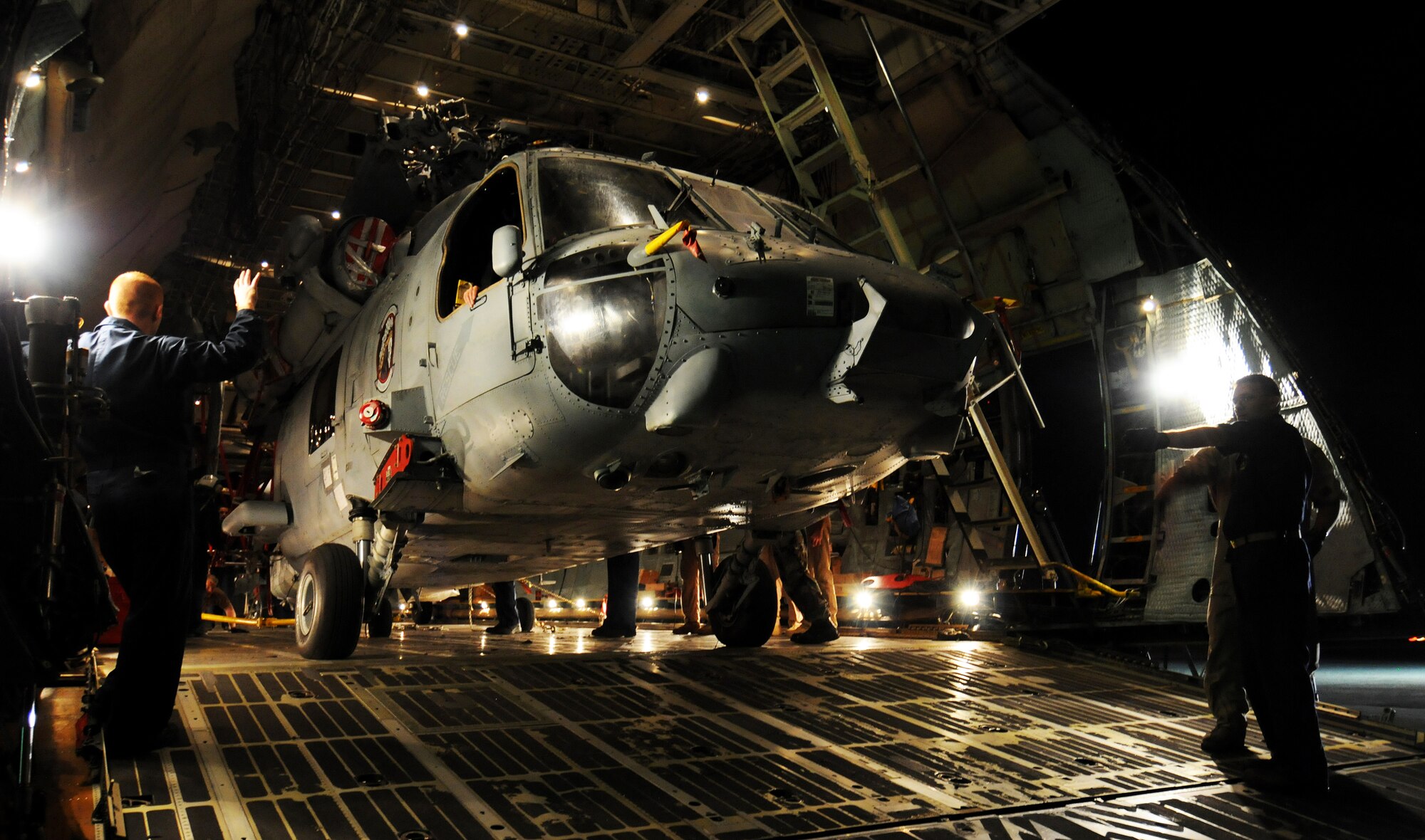 Sailors from Helicopter Sea Combat Squadron TWO-FIVE at Guam's A.B. Won Pat International Airport guide the last of five helicopters into the cargo bay of a C-5 Galaxy March 13 on the flightline at Andersen Air Force Base, Guam.  Airmen from the West Virginia Air National Guard's 167th Airlift Wing and the 734th Air Mobility Squadron at Anderson Air Force Base, Guam, along with the Sailors loaded three MH-60S and two SH-60H helicopters inside the cargo aircraft for transport to Naval Air Station North Island in San Diego.  (U.S. Air Force photo/Airman 1st Class Courtney Witt) 