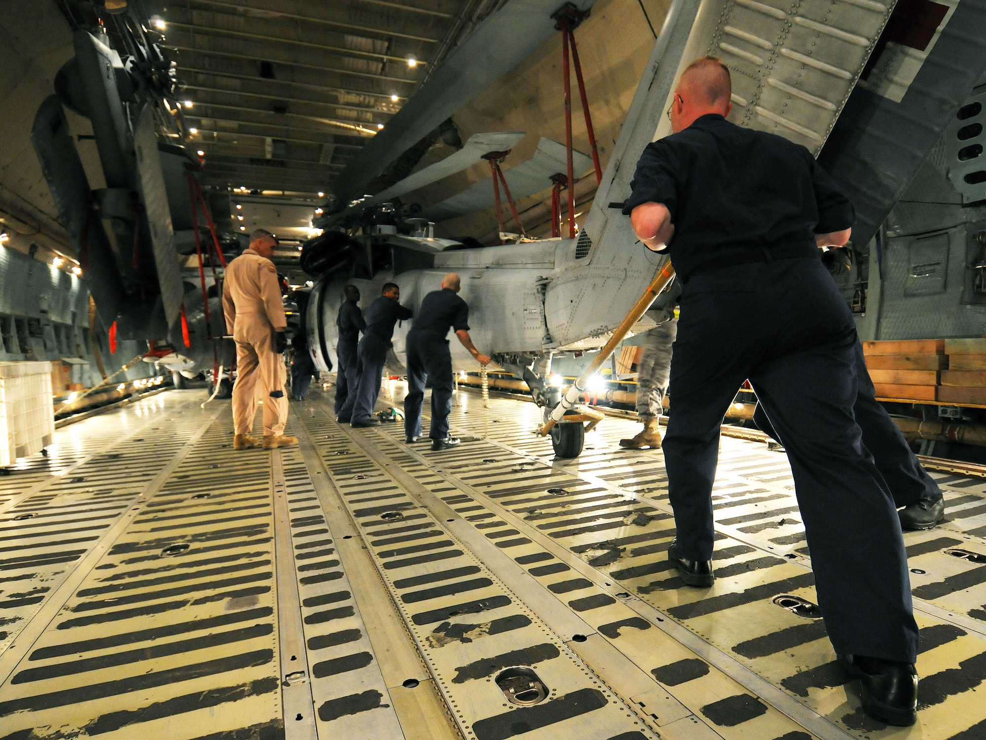Senior Master Sgt. Randall Shafer, a loadmaster with the West Virginia Air National Guard's 167th Airlift Wing, monitors as Sailors from Helicopter Sea Combat Squadron TWO-FIVE at Guam's A.B. Won Pat International Airport position an MH-60S Knighthawk March 13 inside a C-5 Galaxy on the flightline at Andersen Air Force Base, Guam. The Air Force aircrew and the Navy sailors loaded three MH-60S and two SH-60H Sea Hawk helicopters inside the cargo aircraft for transport to Naval Air Station North Island in San Diego.  (U.S. Air Force photo/Airman 1st Class Courtney Witt) 