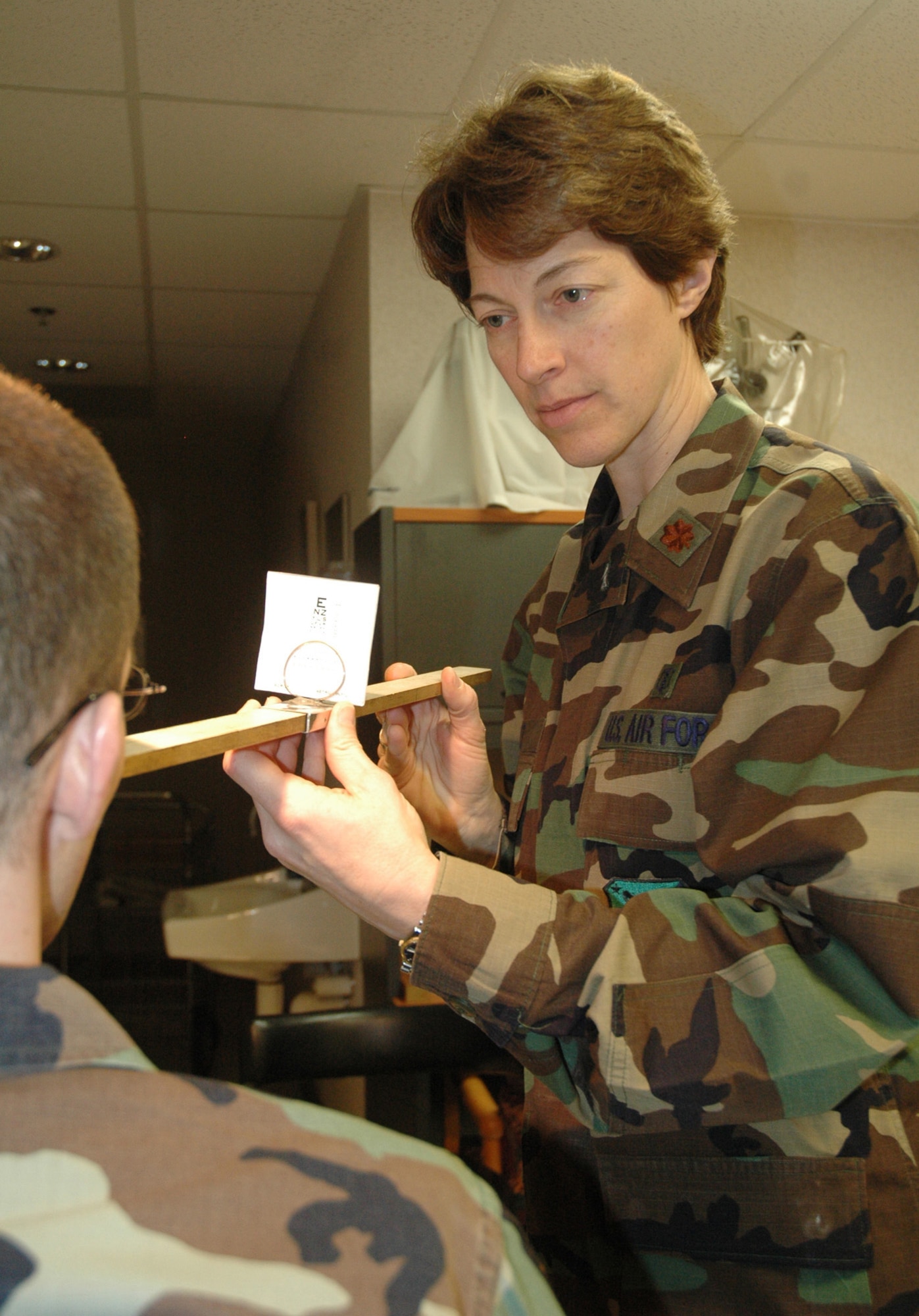 DOVER AIR FORCE BASE, Del. -- Air Force Reservist Maj. Stephanie Holt, 512th Aerospace Medicine Squadron chief of optometry, ensures Tech. Sgt. Joseph Smith-Basinger, 512th Aircraft Maintenance Squadron crew chief, meets the vision criteria to cross-train into a flight engineer position March 7 during the 512th Airlift Wing Unit Training Assembly. Major Holt is an optometrist at the Eye Institute of Salus University and works part-time for two retinal specialists in Philadelphia. The optometry department examines patient?s vision acuity, depth perception, color vision and intraocular pressure. (U.S. Air Force photo/Senior Airman Andria J. Allmond)