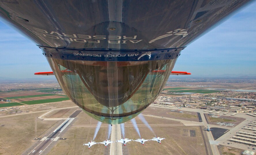 Ed Hamill, in the Air Force Reserve biplane, flies with the U.S. Air Force Thunderbirds over Luke Air Force Base, Ariz., March 18. Both the Thunderbirds and Mr. Hamill will be performing at "Thunder in the Desert," Luke's two-day open house and air show this weekend. As the U.S. Air Force Air Demonstration Squadron, the Thunderbirds perform precision aerial maneuvers demonstrating the capabilities of Air Force high performance aircraft to people throughout the world. Mr. Hamill is an Air Force Reserve lieutenant colonel who serves as an instructor pilot with the 944th Fighter Wing at Luke AFB. He performs at air shows around the country, highlighting the history of air show flying while promoting the Air Force Reserve. (Courtesy photo/Ed Hamill)