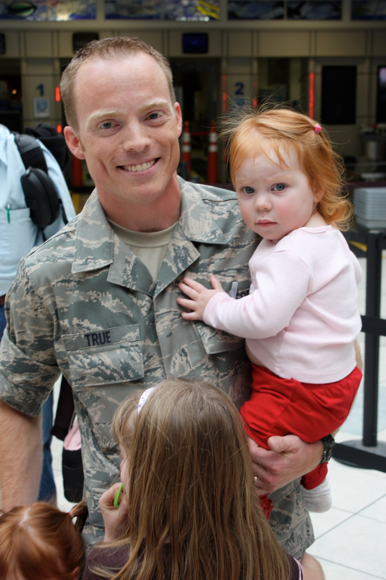 Tech. Sgt. Jeremiah True, a saxophonist with the Air Force Band of Flight, reunites with his three daughters after completing a 60-day deployment. (Air Force photo by Maj. Mike Mench)