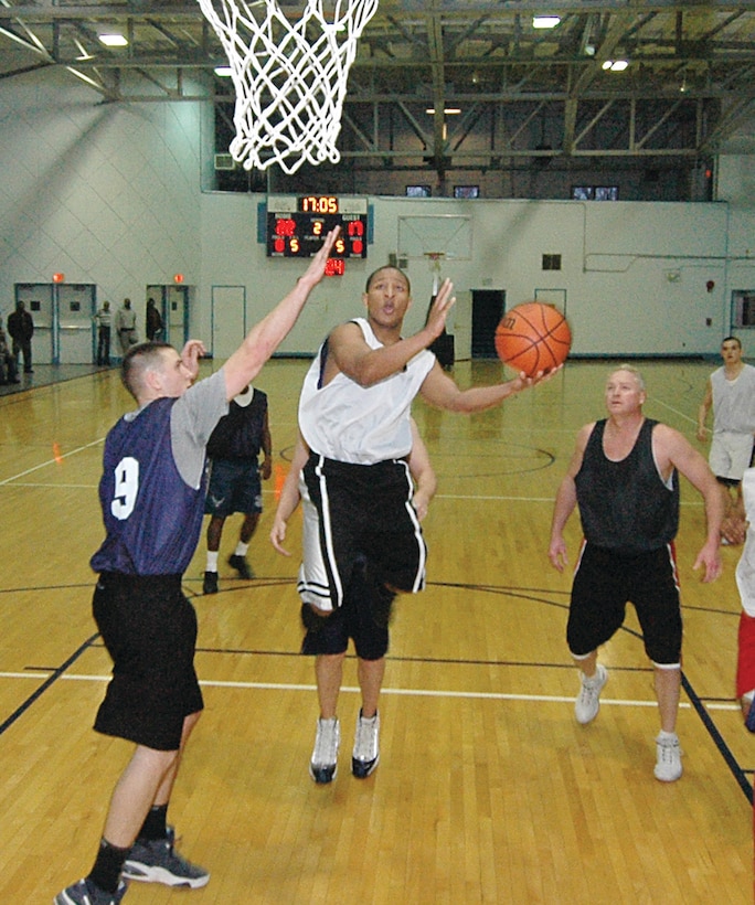 Vincent Jones, 779th Medical Group guard, penetrates the defense of Shane Simpson, 316th Civil Engineer Squadron forward, left, during the Intramural Basketball Championship game held at the East Fitness Center, March 12. The779 MDG beat the 316 CES 44-33 to win the title. (U.S. Air Force photo/ Bobby Jones)